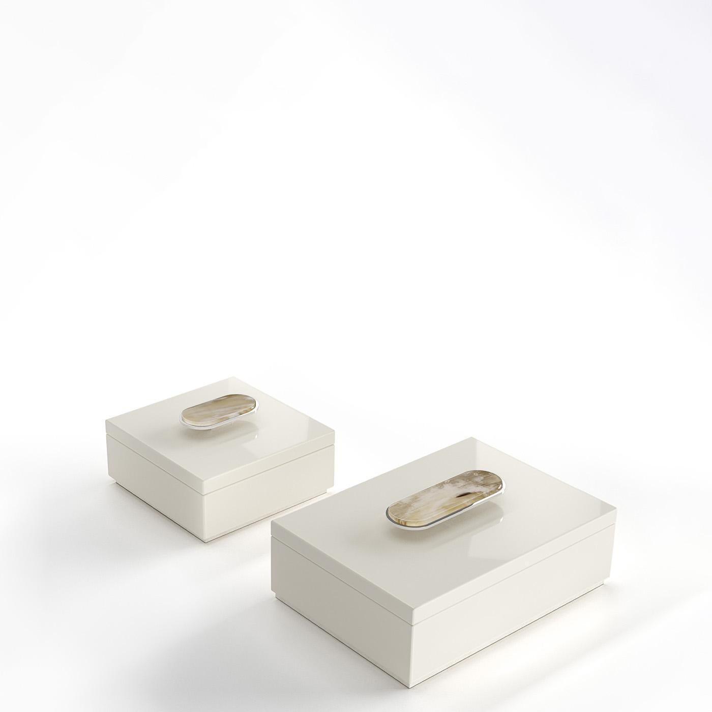 La boîte Priora est un accessoire polyvalent et élégant, conçu pour ranger avec le plus grand soin les objets qui vous sont chers. Réalisée en bois laqué ivoire brillant, la boîte se distingue par les détails en Corno Italiano et en laiton chromé