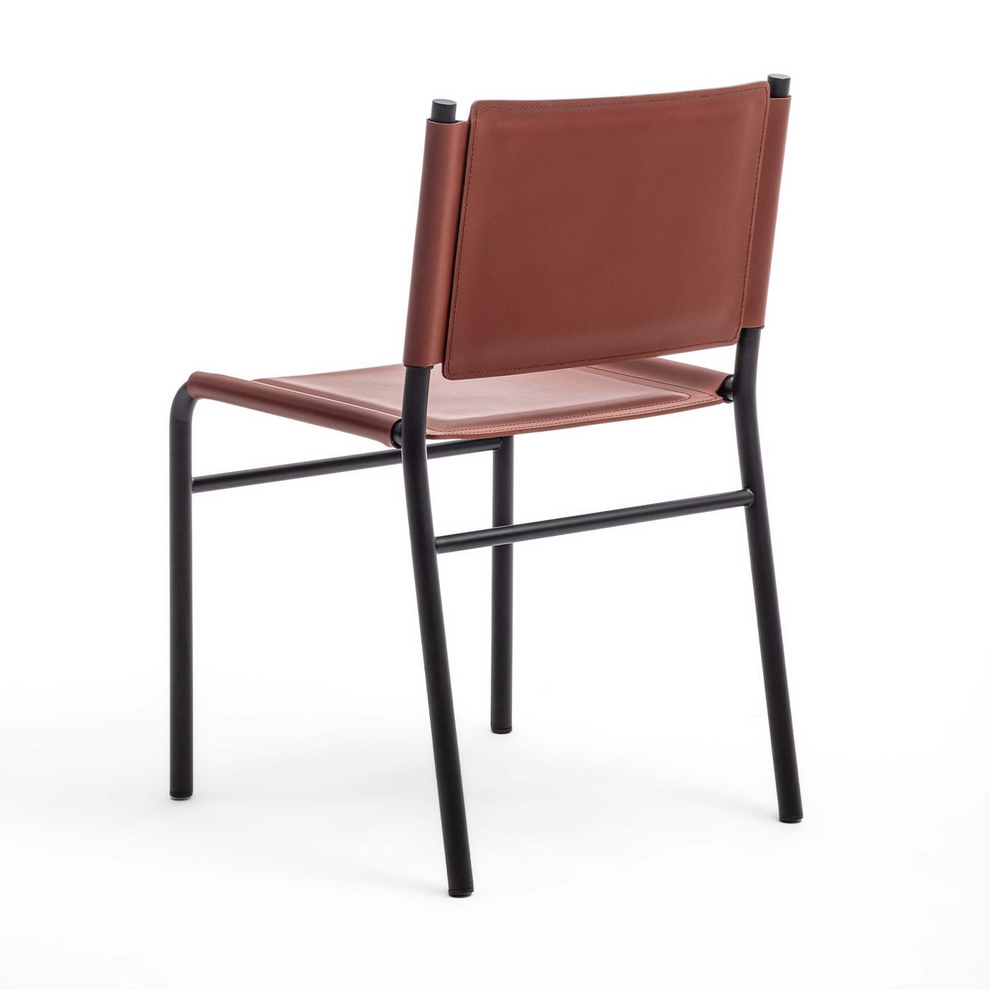 La chaise Pris présente une élégante structure en métal tubulaire peinte en noir, alliant un design moderne à un savoir-faire raffiné. L'assise et le dossier sont généreusement paddés et revêtus d'un luxueux cuir rouge, offrant à la fois confort et