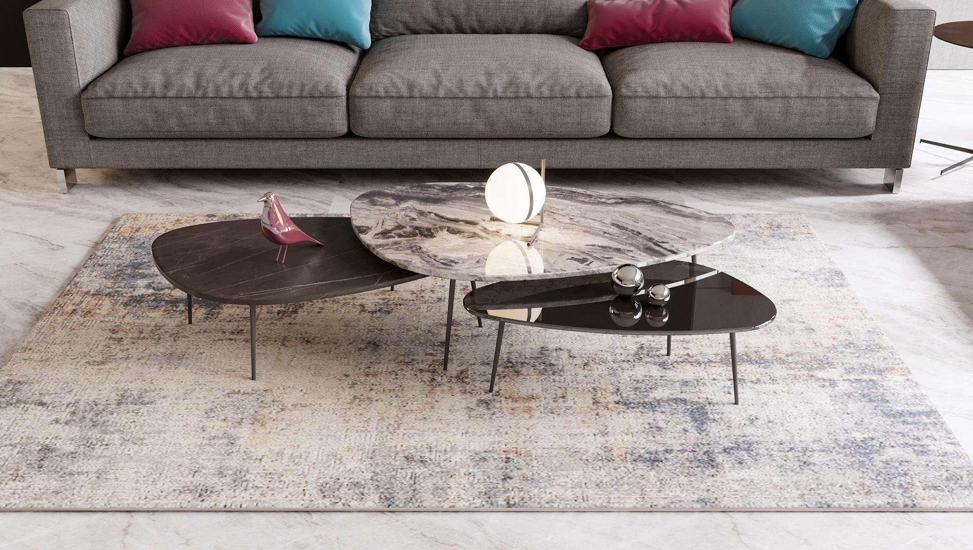 A set of 3 coffee tables of different top material and variable height dimensions. Each table top has an asymmetrical elongated egg shape that is made of either trendy marble or glass carried by 3 cone-shaped metal legs. The set is suitable for