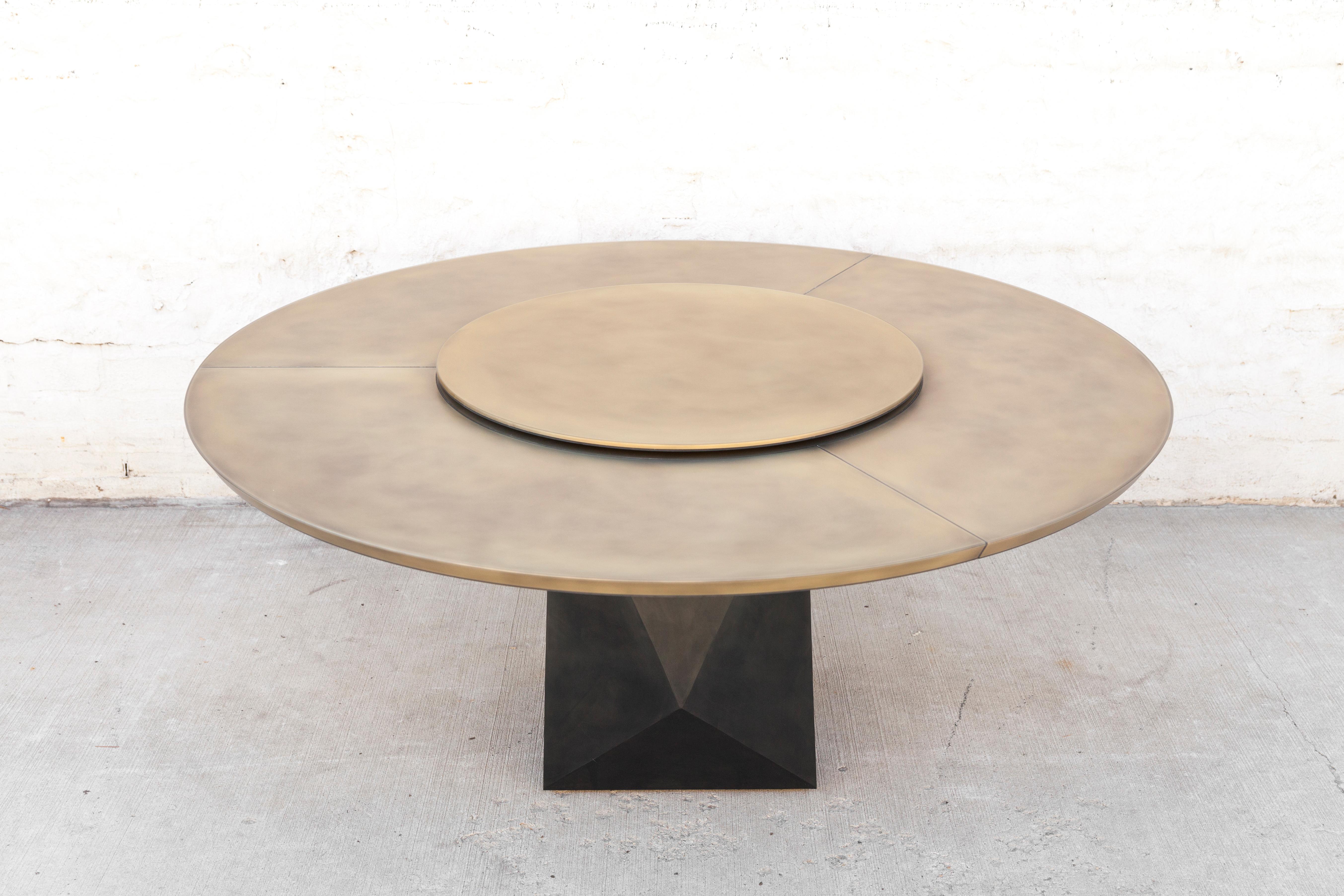 La table à manger chic Prism est à la fois élégante et fonctionnelle. Le plateau en bronze enrobé de résine époxy comprend un plateau tournant et est associé à une base en acier noirci à facettes. Note : Peut être réalisé sans couture dans certaines