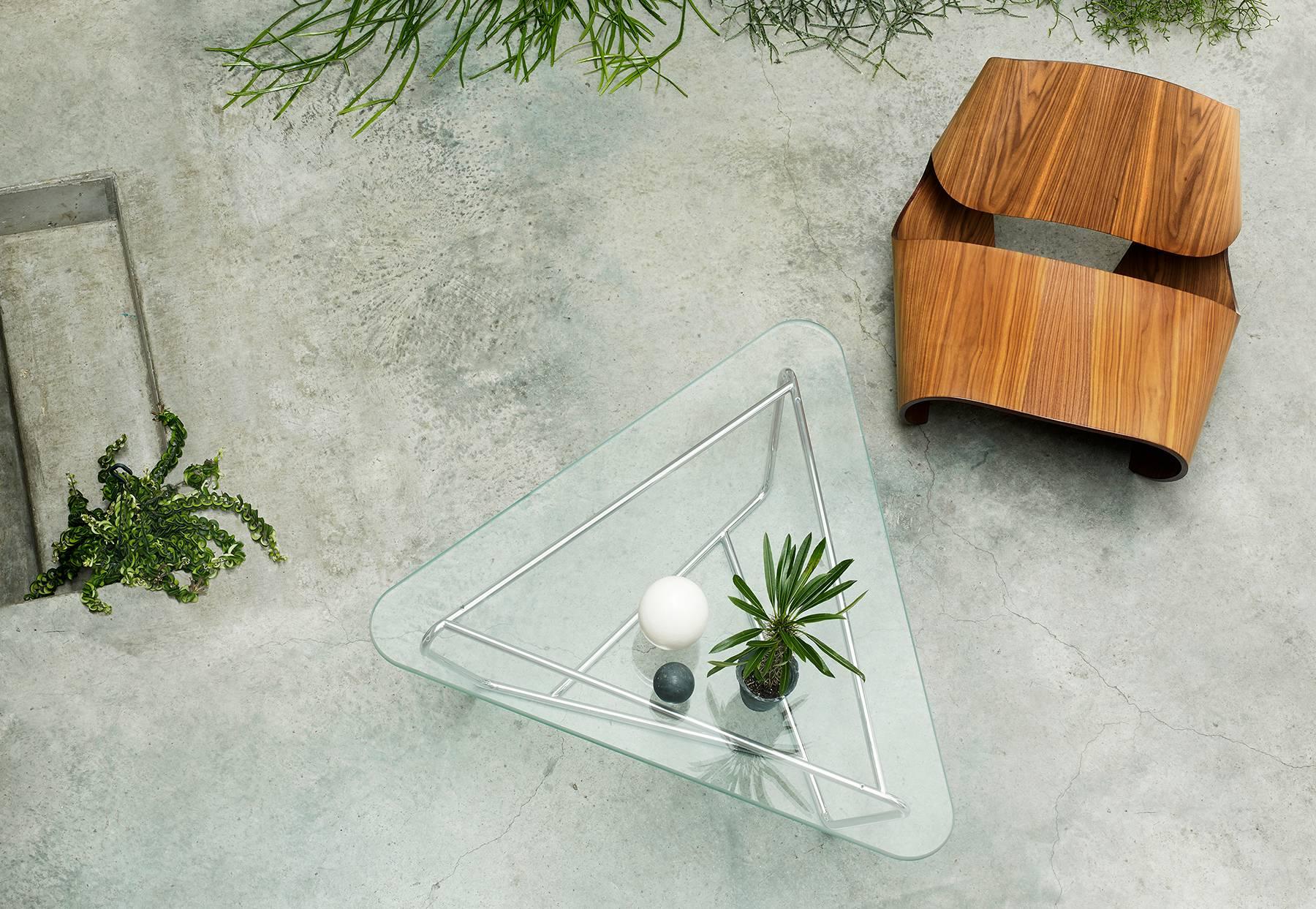 La table basse contemporaine Prism possède une base de configuration géométrique faite d'un cadre tubulaire en acier inoxydable formant un motif triangulaire entrecroisé. La table est complétée par un plateau triangulaire à bord arrondi en verre