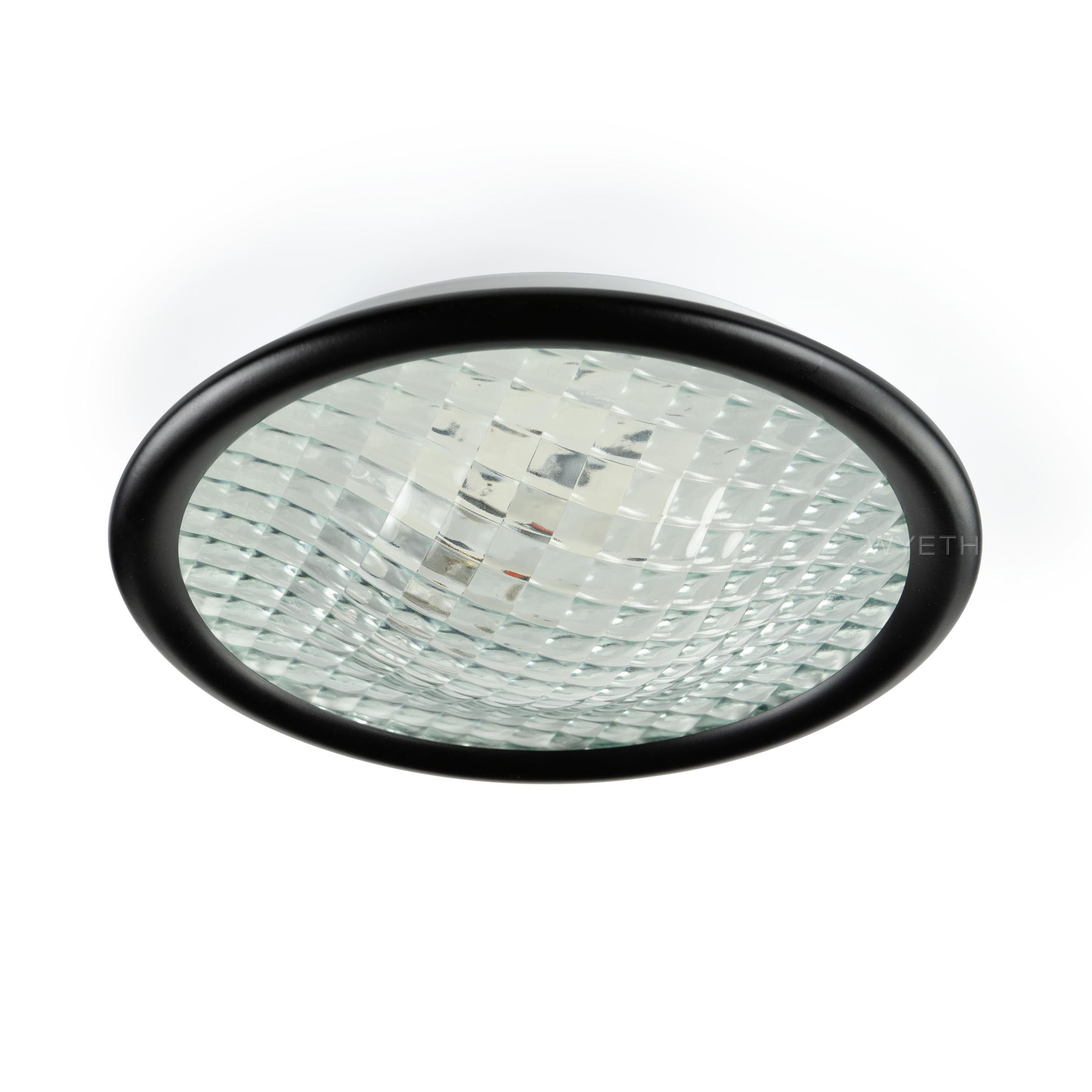 A flush mount fixture with an extruded prism glass lens and black frame.