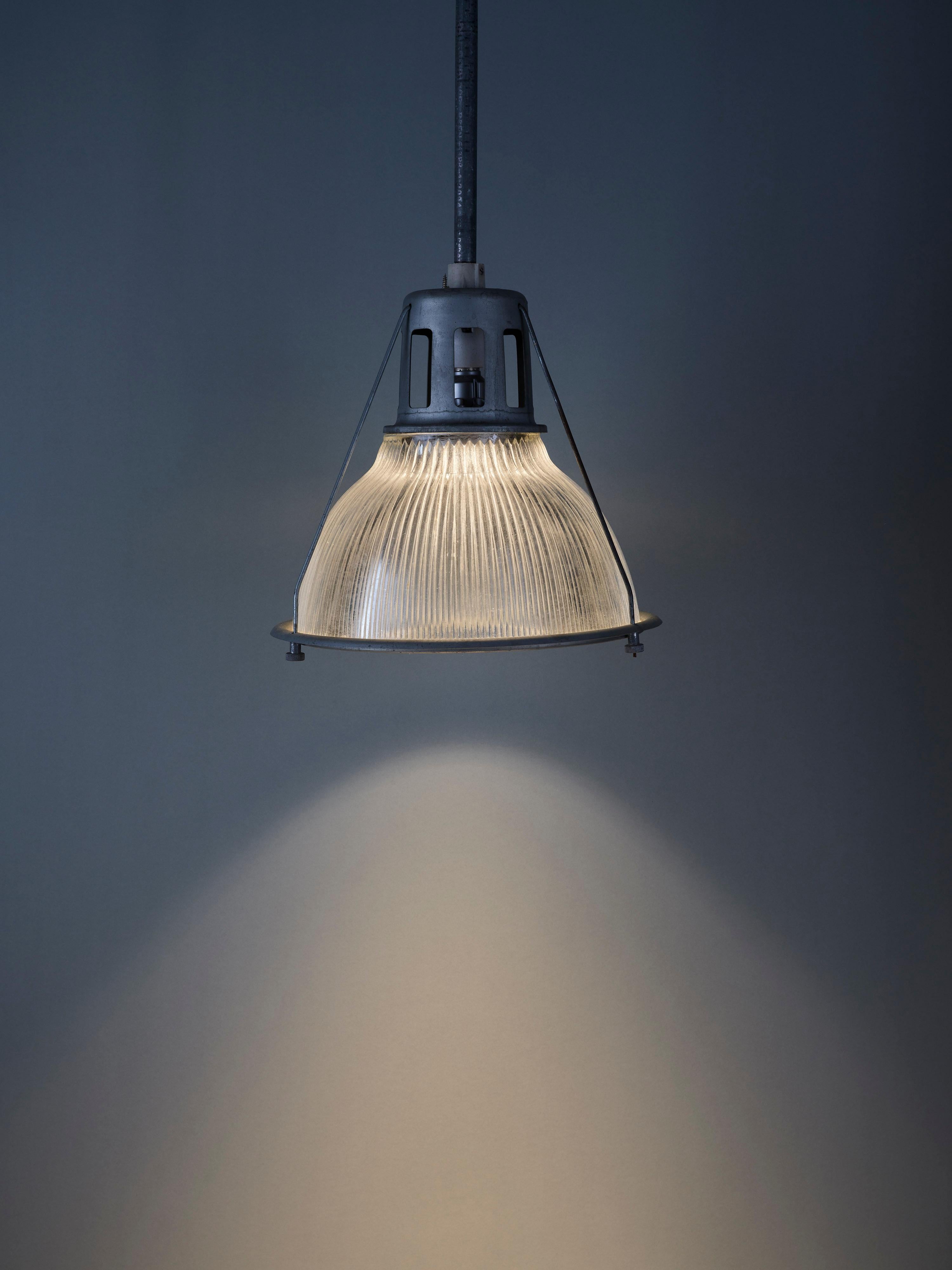 Crafted by renowned company Holophane, pioneers of prismatic lighting in late 19th-century US, this industrial light boasts historical significance. Its prismatic glass disperses light evenly, offering gentle illumination that remains easy on the