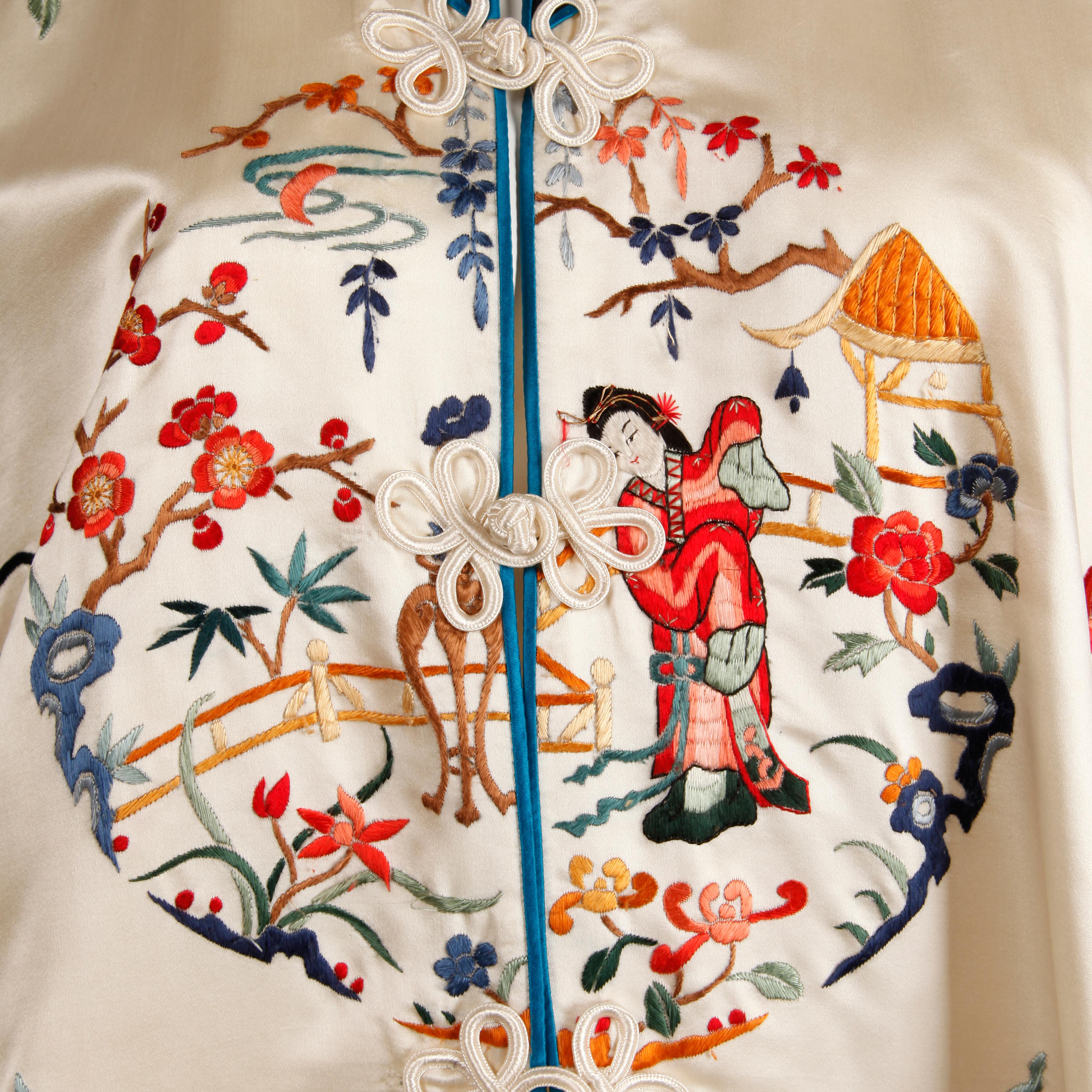 Stunning and pristine 20th C. Chinese silk satin robe with colorful embroidery of figures and cherry blossoms. Fully lined in silk with front frog button closure. The bust measures 44