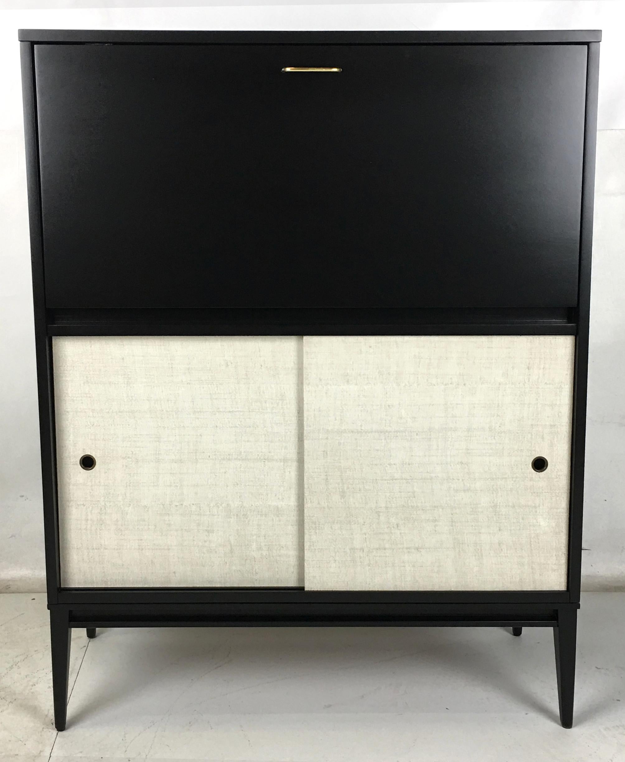 Up for bid is this handsome drop-front secretary from the Planner Group by Paul McCobb for Wichendon Furniture. The piece has been meticulously restored and refinished and couldn't be in nicer condition. The enameled Raffia doors are clean and