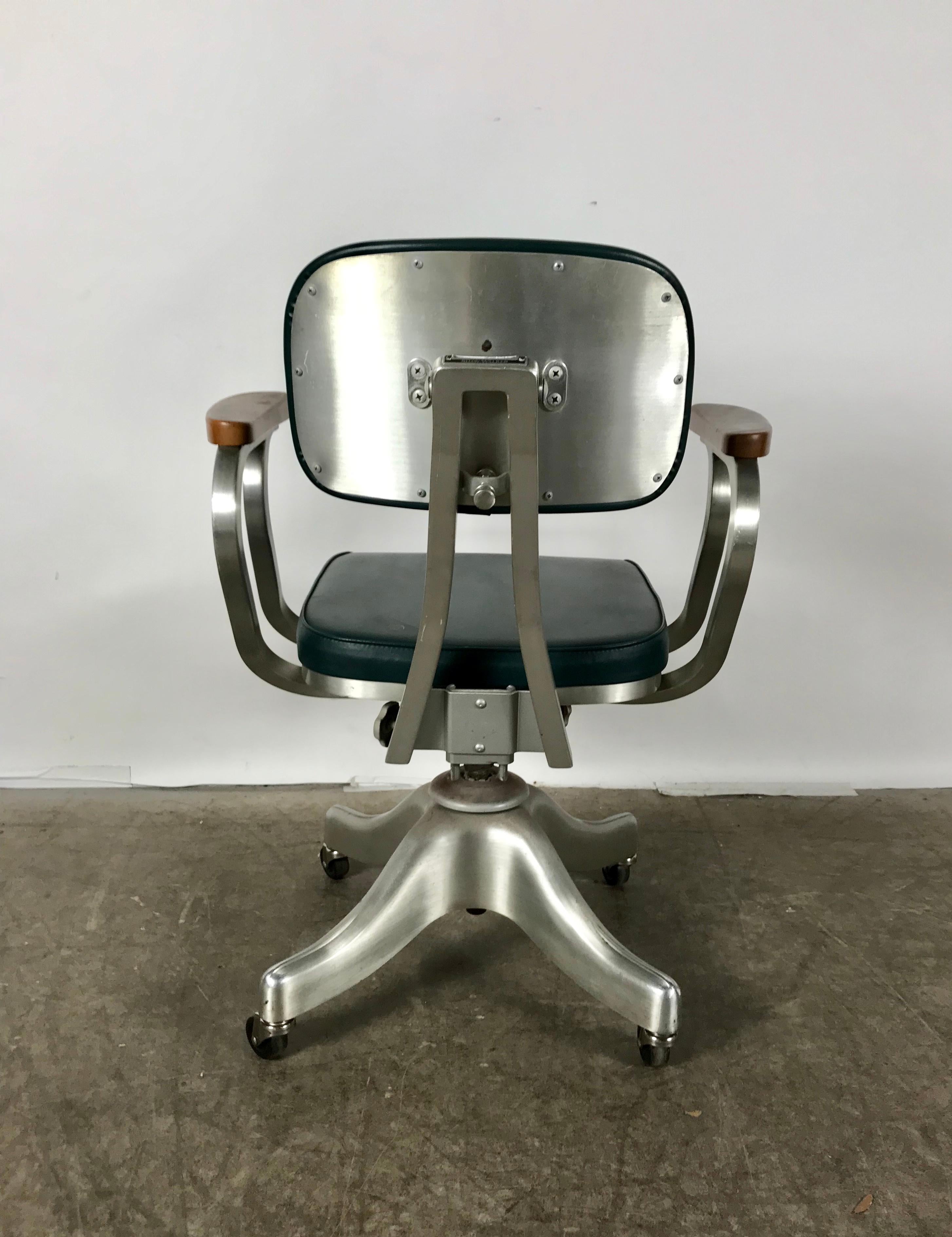 Shaw Walker aluminum rolling desk or task armchair, late 1940s. Remarkably, pristine original condition, Polished aluminum Propeller base,stylized arms. Maple or birch wood arm rests, original green Naugahyd, fully adjustable, retains original Shaw