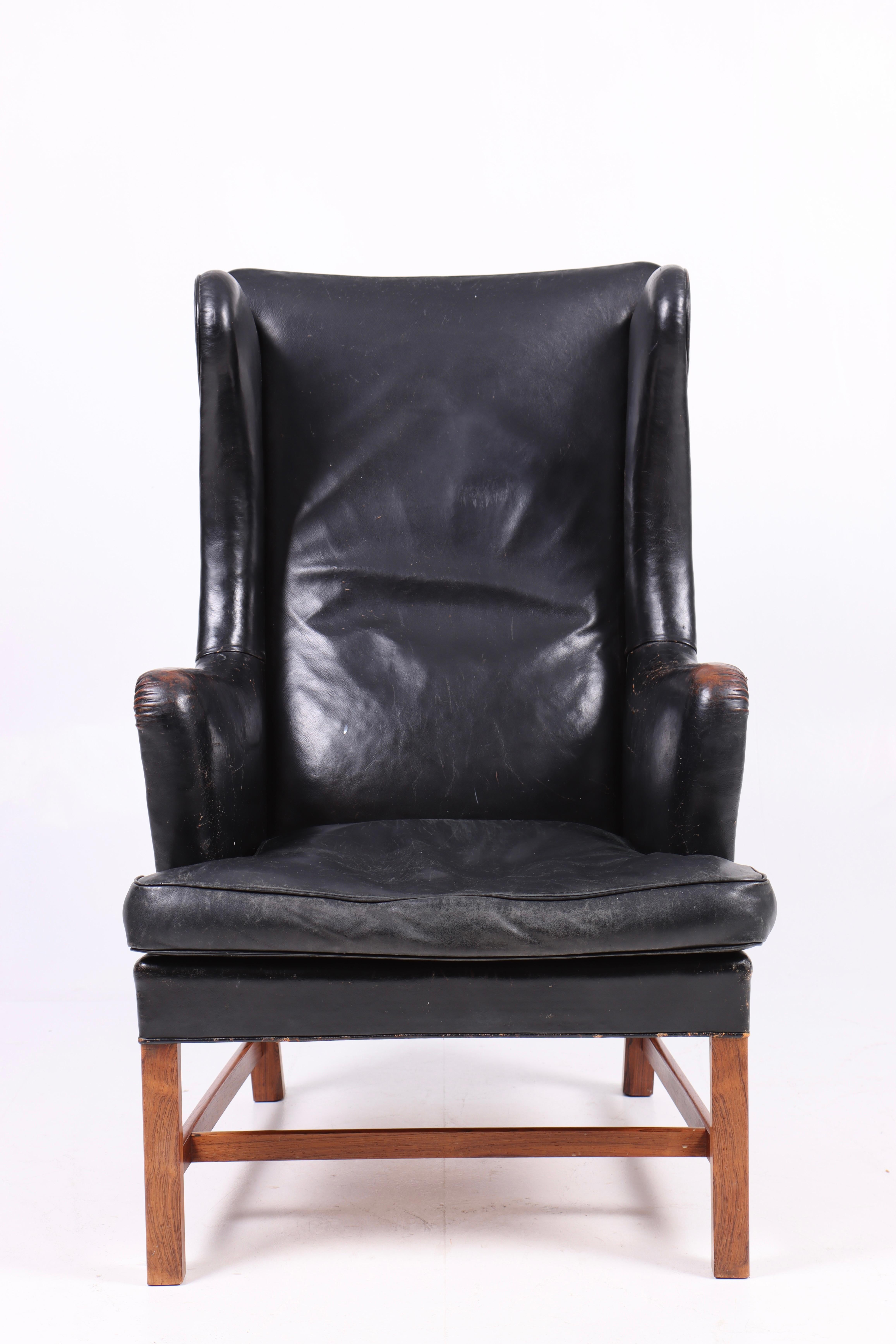 Great looking wingback chair in patinated black leather, designed by Kaare Klint for Rud Rasmussen in 1946 model 5313. Made in Denmark. Original condition.