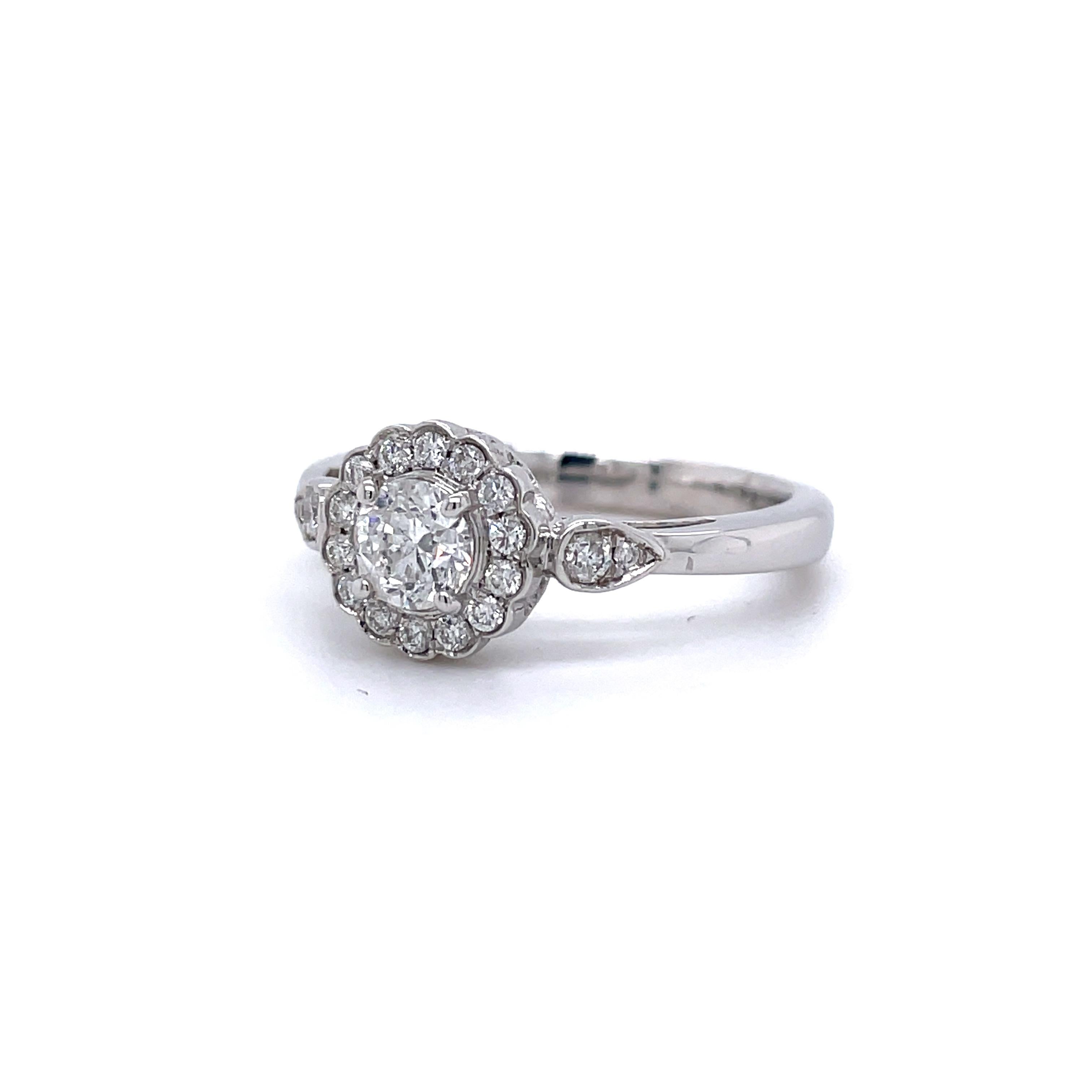 This lovely diamond ring has a beautiful 0.48 ct (G-H Color, I1 Clarity) round brilliant diamond in the center with an additional 18 diamonds weighing 0.24 cttw (H-I Color, I1-I2 Clarity) accenting the sides and the shimmering scalloped halo. The