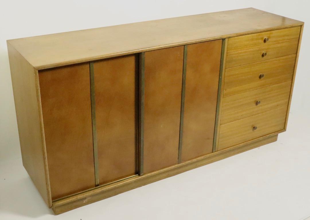 Great architectural midcentury credenza by recognized master of the style Harvey Probber. This model features two sliding leather fronted doors, which open to reveal interior storage with slide out drawers, flanked by for deep drawers, to provide