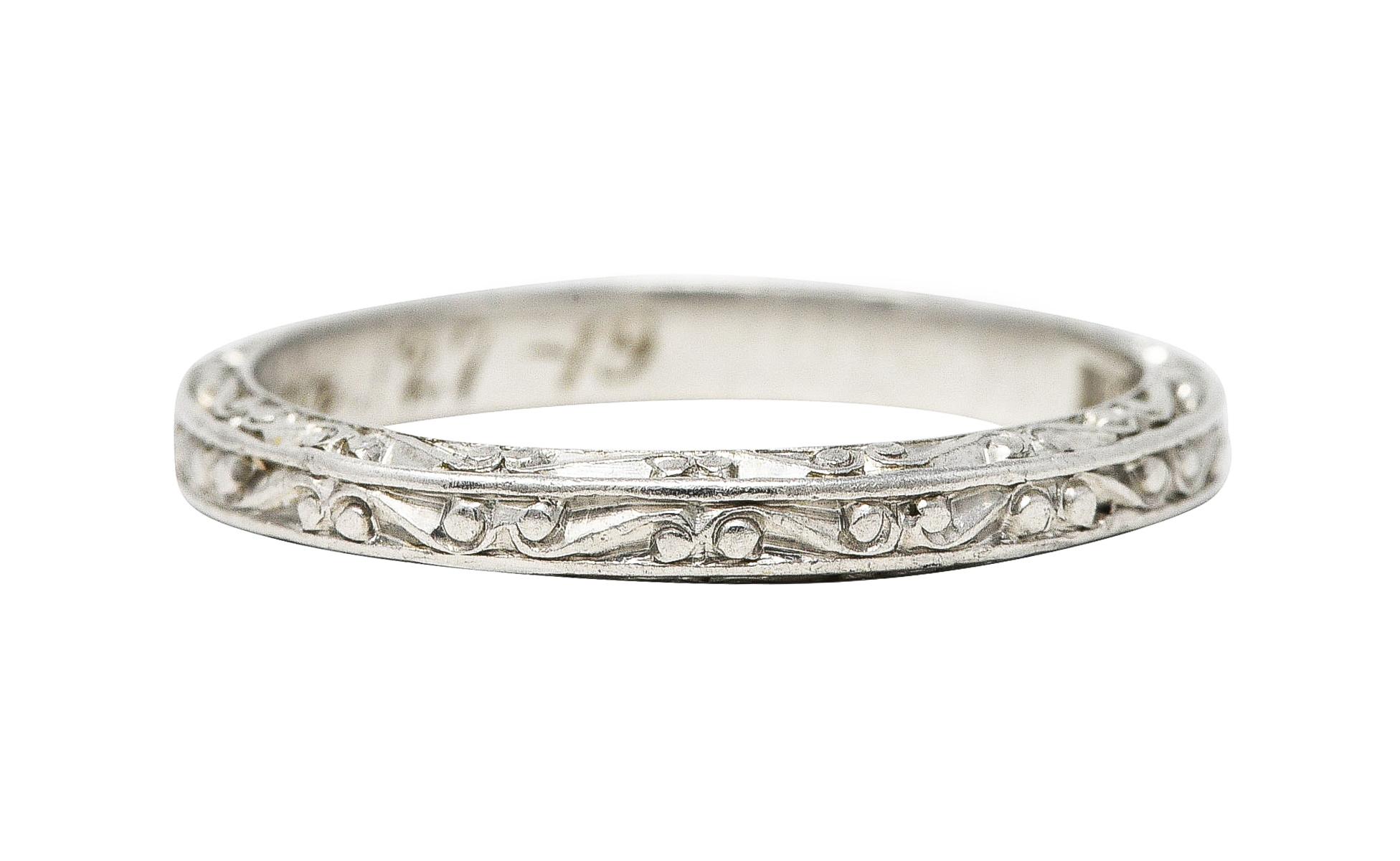 Band ring features a grooved scrolling motif fully around. With scroll motif profile. Inscribed 'BMG to FMH Apr. 27-19'. Tested as platinum. With maker's mark for Abel Bros. Circa: 1919. Ring size: 5 and not sizable. Measures: North to South 2.2 mm