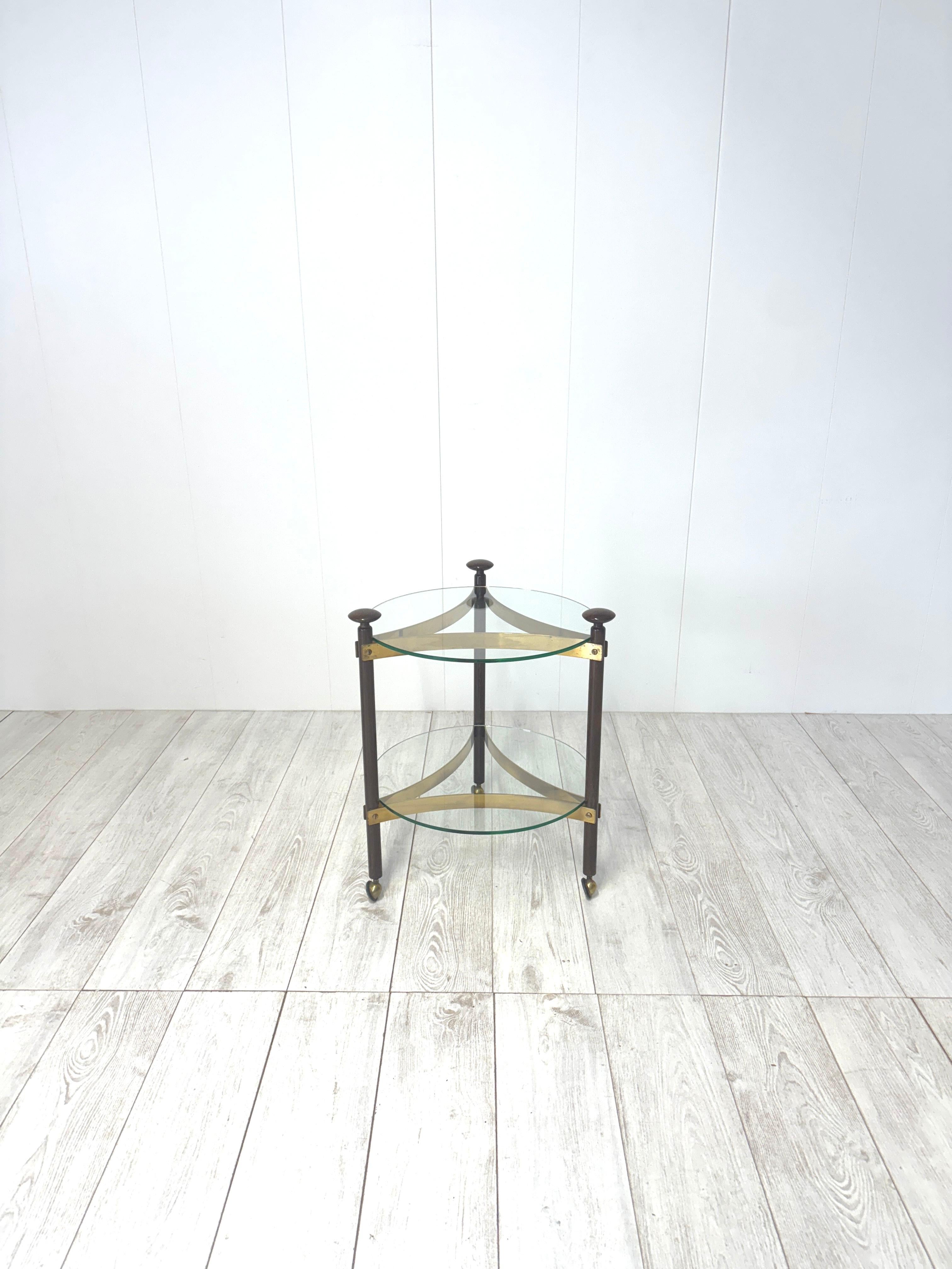 Chariot ou table d'appoint à roulettes, produit en Italie dans les années 1960.
Cadre en laiton et en bois, plateaux en verre.

Bon état
