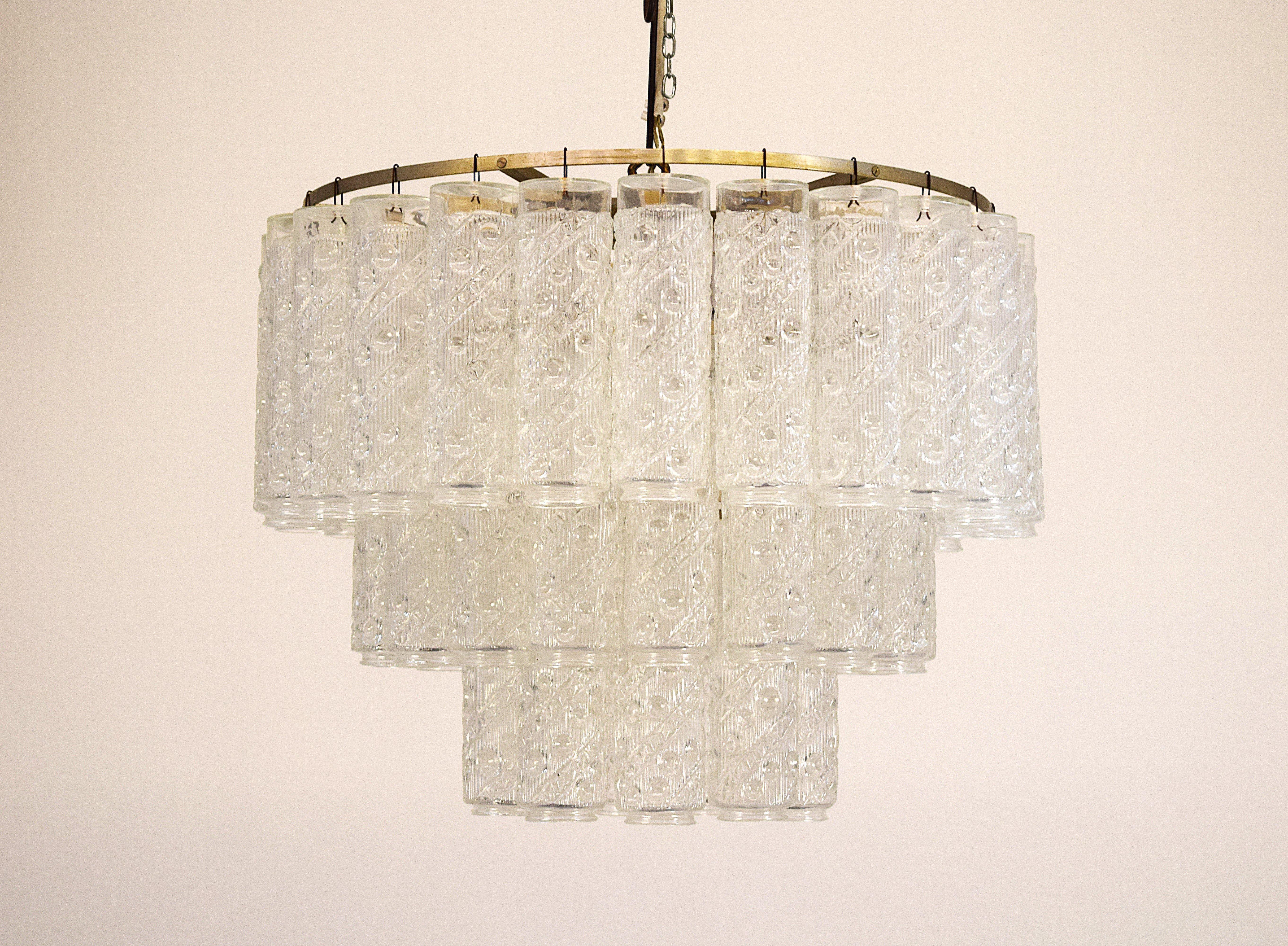 Elegant Italian chandelier from the 1960s, made of worked glass and metal. The structure, composed of 50 decorated glass tubes (h 21 cm, Ø 6 cm), is developed on several levels, creating a striking play of light and transparency. The total diameter