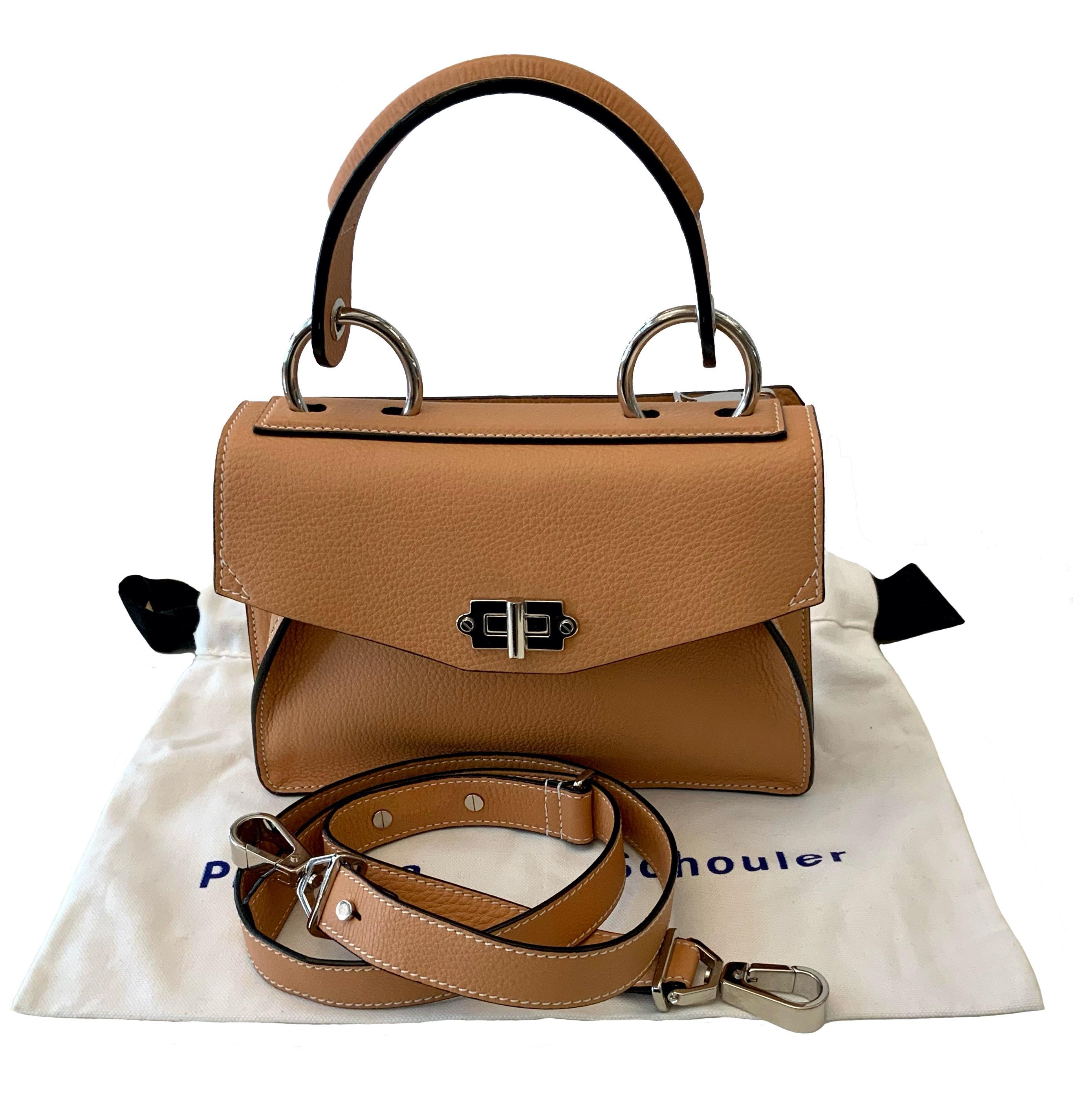 This pre-owned but new Hava Top Handle is crafted in a natural color calfskin leather.
It features custom designed ring hardware and a turnlock closure and signature design elements: topstitching, round studded outlining, folded gusset structure. It