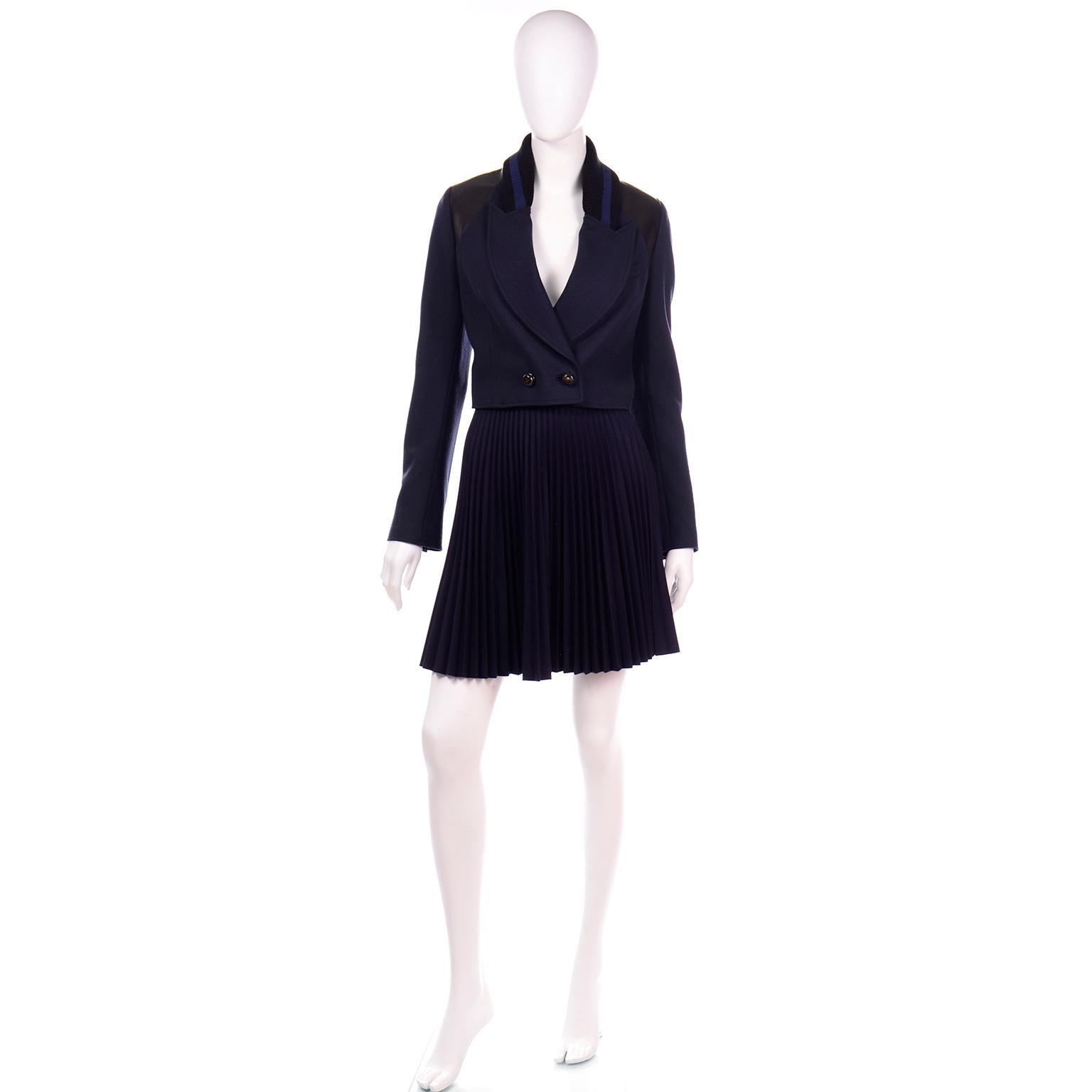 This is a great Proenza Schouler 2 piece suit with a cropped varsity style blazer jacket and an accordian pleated skirt. The jacket has a navy and black ribbed knit collar with a pointed notch collar with a single breast pocket. The shoulders have