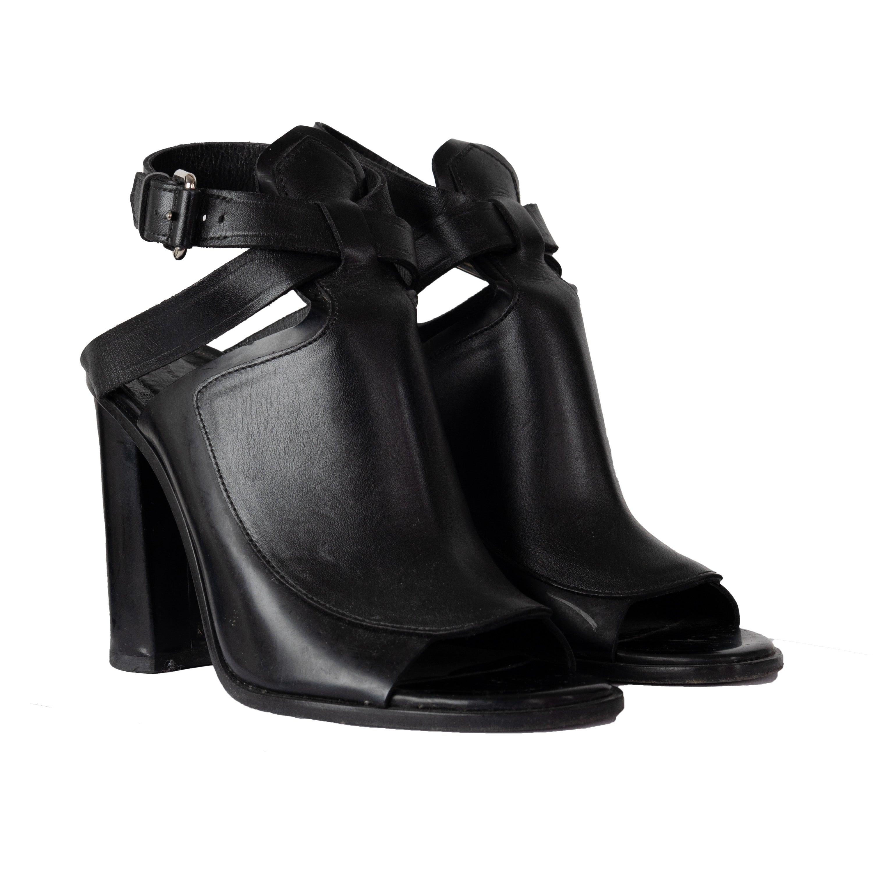 Les sandales à talon ouvertes de Proenza Schouler sont fabriquées à 100 % en cuir de première qualité pour une tenue confortable et durable. Ils sont de couleur noire classique et se ferment par une boucle argentée de bon goût. Le talon carré ajoute