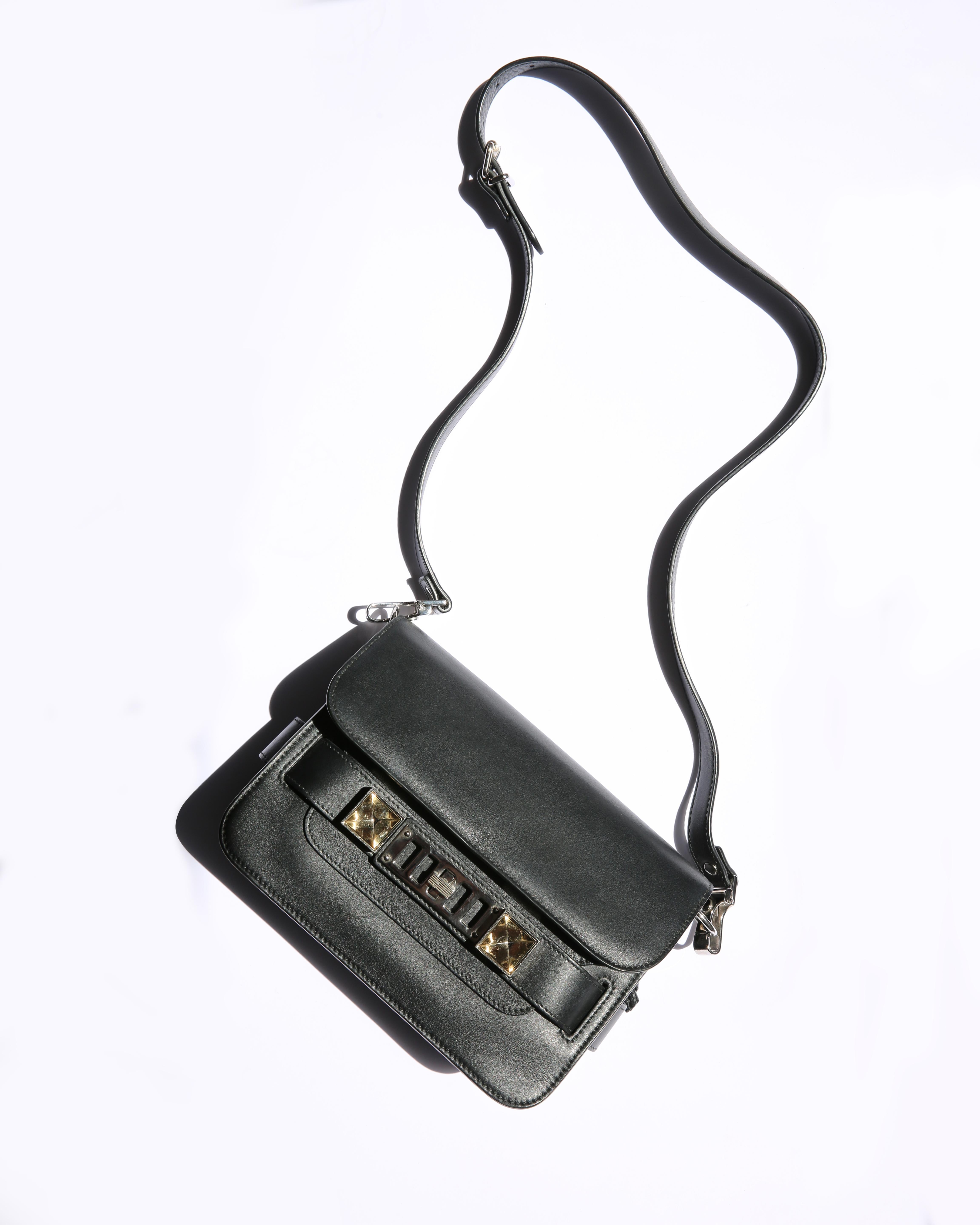 Proenza Schouler PS11 mini classic shoulder bag
Detachable strap means this can be worn as a clutch
Black smooth leather
Boxy style bag with a metallic pate and twist lock fastening to its front that is accented with silver tone stud detailing 
Calf