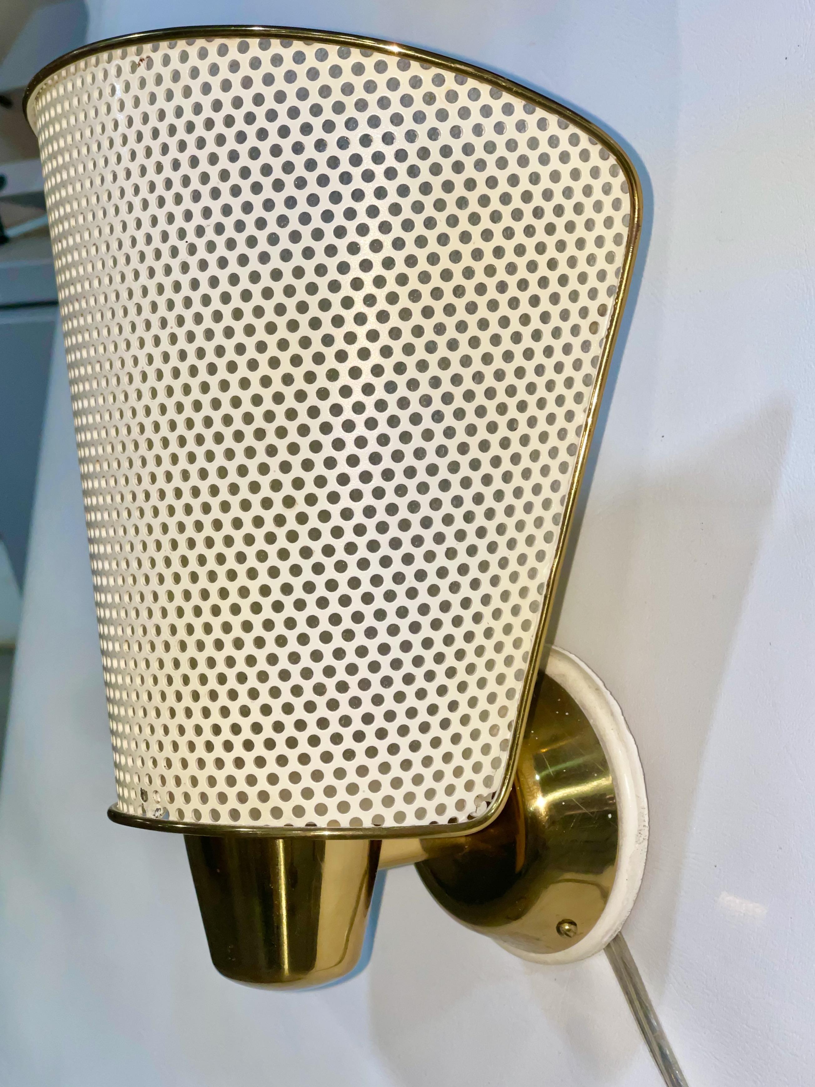 Seldom seen single brass sconce with perforated and enameled metal curved shade designed by Prof. Carl Moor for BAG Turgi, Switzerland.
Takes E17 intermediate Edison base light bulb up to 75 watts.
Comes with the original white painted wood mounting