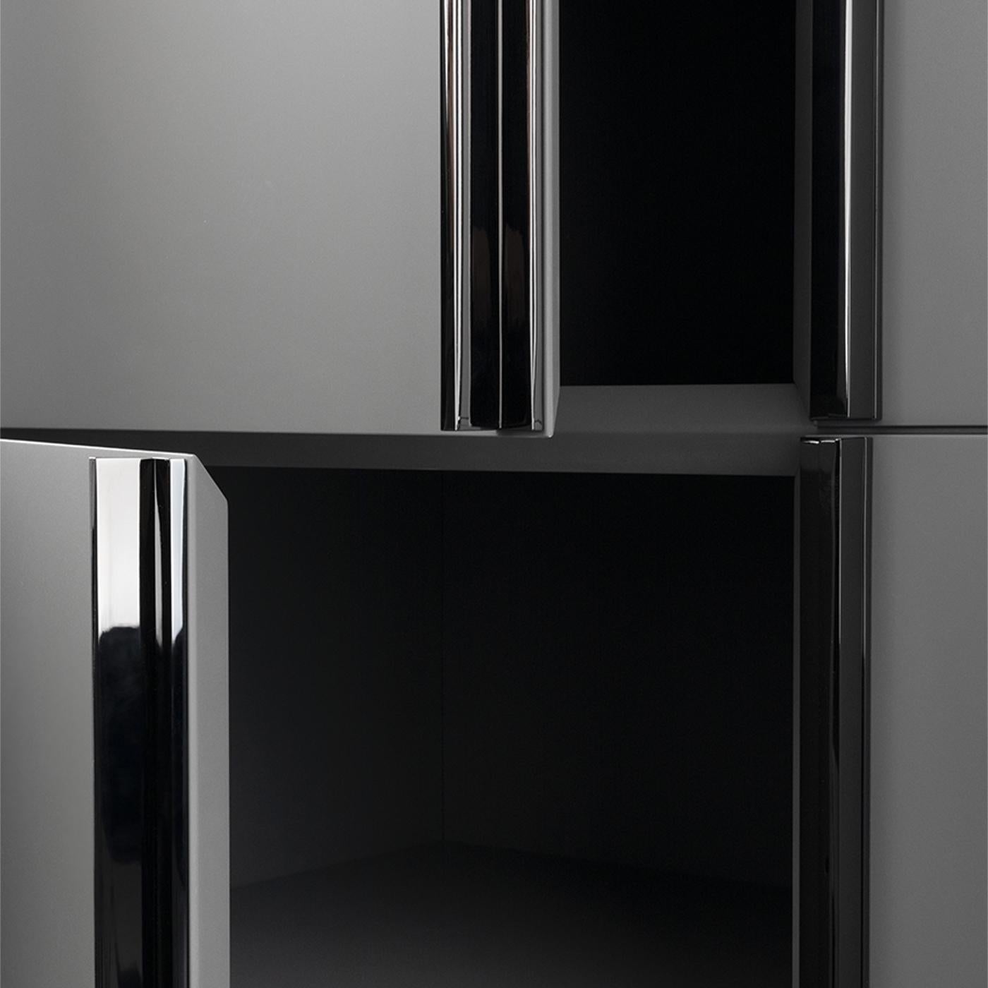 Elegant in its rigorous lines and matte dusty-gray lacquer, this cupboard makes for a precious addition to contemporary interiors. Black nickel is the glamorous finish selected for both the linear handles and crossing base elements, adding a