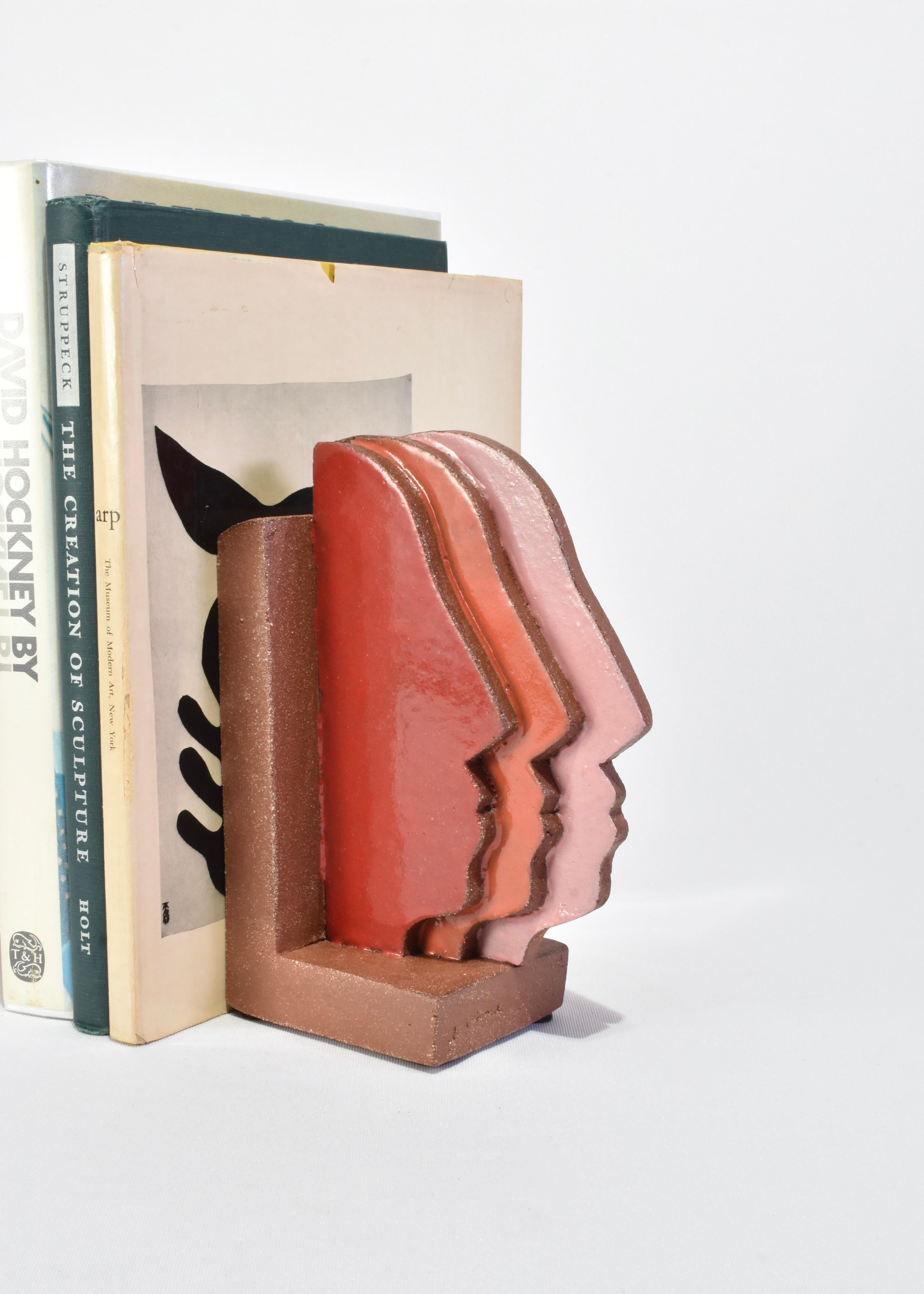 Handmade slab-built bookends with a multiple face profile design in red, orange, and pink, set of two.

Please note that this item is handmade and therefore unique; slight variations in color and shape are to be expected.
