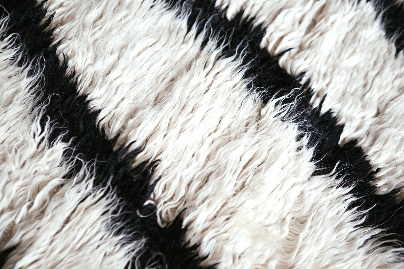 The deeply contrasting and luxurious mohair features prominently in the beauty of Profile. The abstract black and white strokes lose their edge as the fibers fall over each other at the edges. The surface is ever changing. A brushing turns the