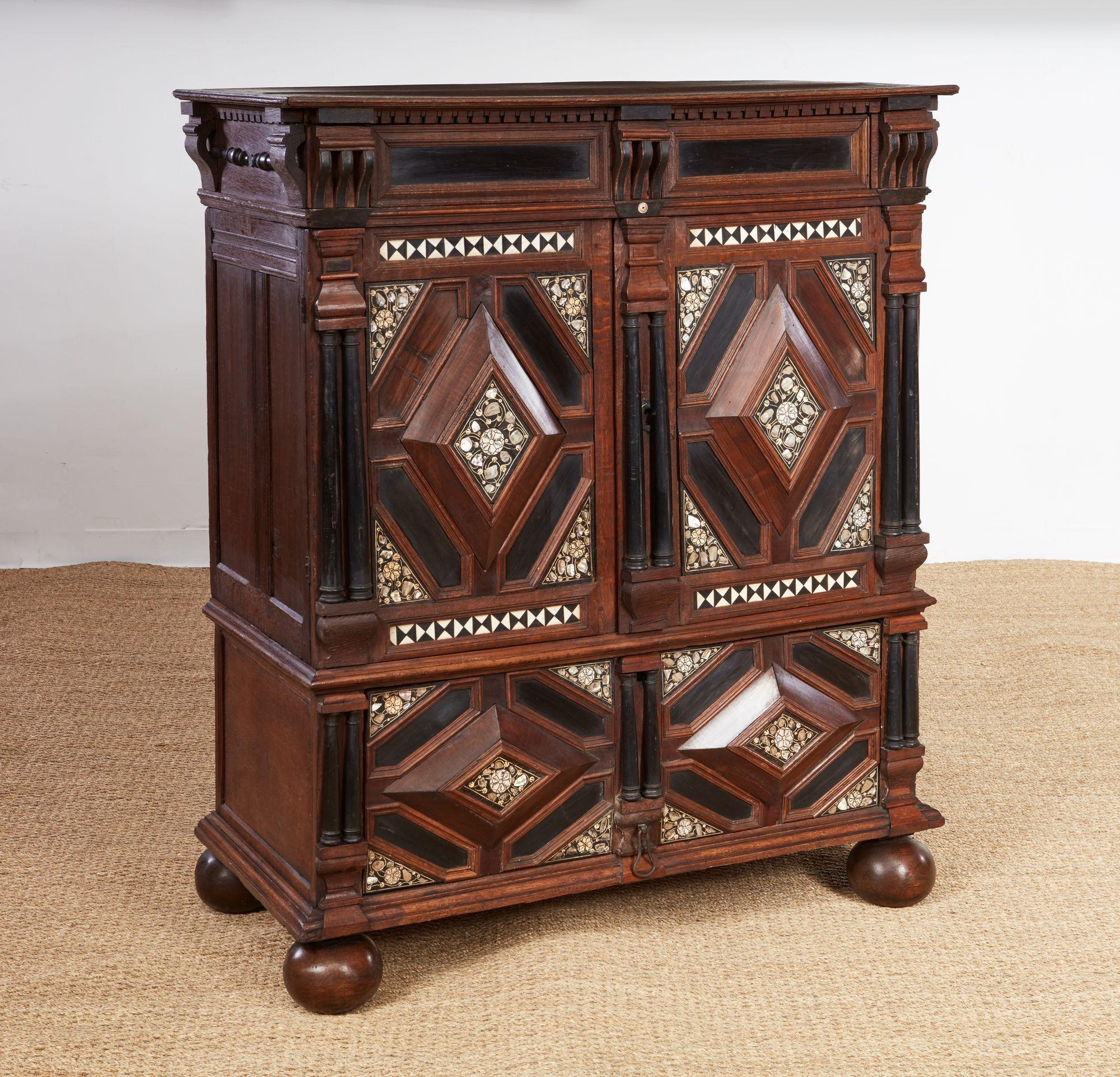 Armadio o cassapanca coperta del periodo Charles II, circa 1660, riccamente decorata con pannelli geometrici a rettangolo e diamante intarsiati con madreperla, osso e legno ebanizzato. L'armadio è composto da tre parti separate e impilabili, che lo