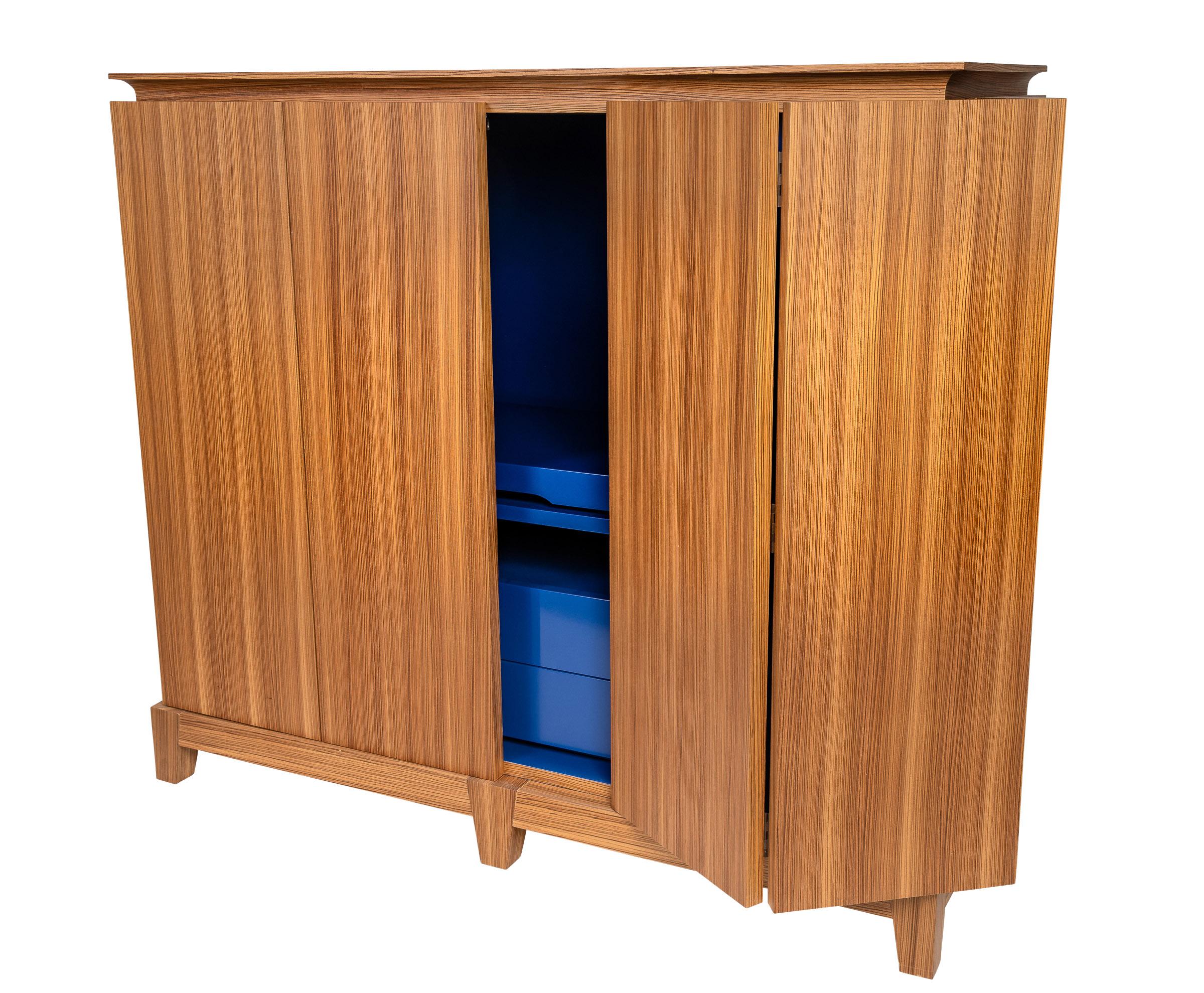 This beautifully crafted cabinet from Promemoria has a luminous secret. When you open the TV cabinet, you can see the Yves Klein blue lacquer finish on the inside, which makes this piece unique. The interior has integrated shelves and drawers as