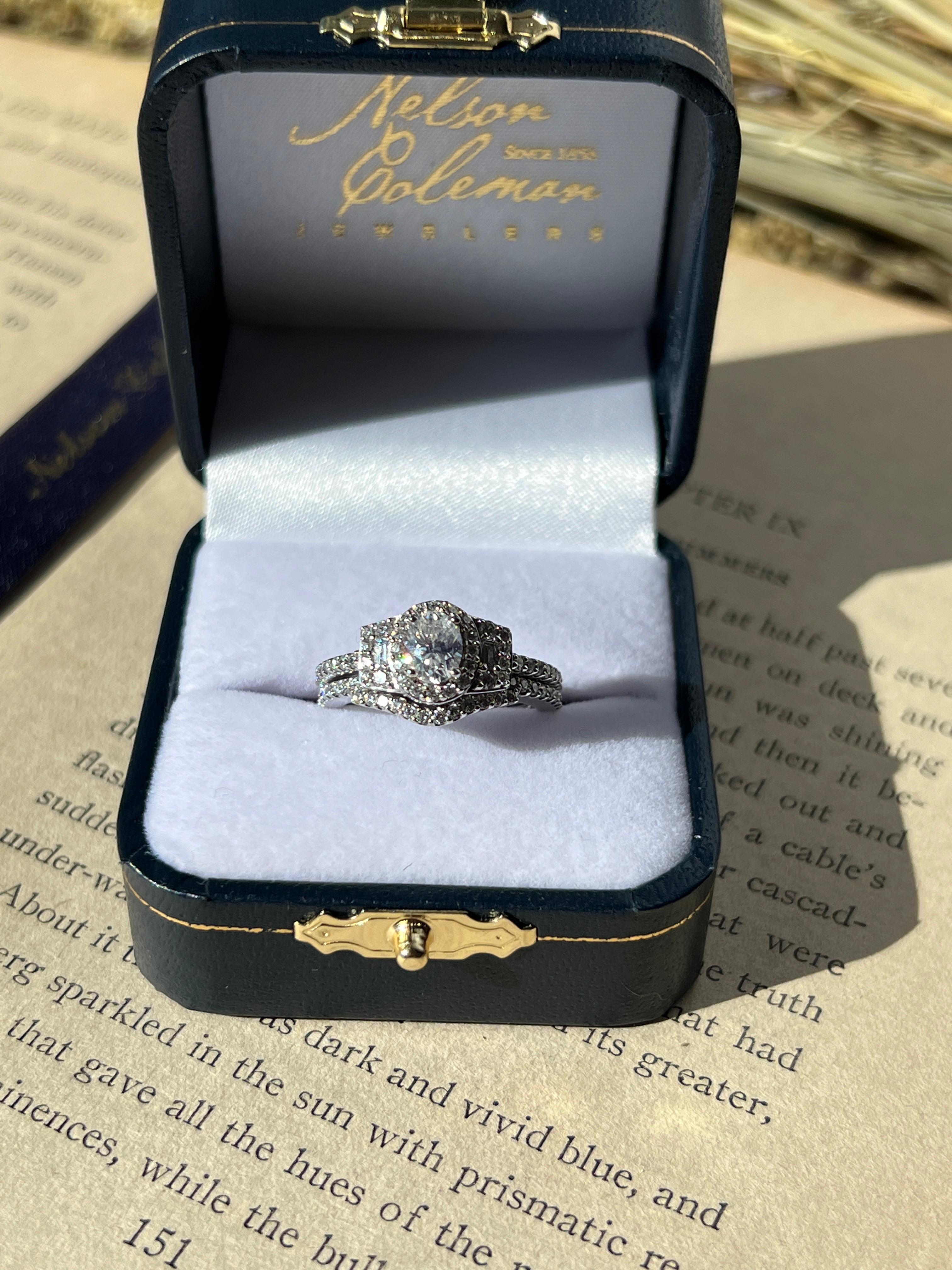 This contemporary 14-karat white gold Promezza wedding set is a dazzling symbol of love and commitment. The engagement ring features a 0.62-carat oval diamond with G color and VS1 clarity, certified by GIA lab report #215576421. Surrounding it are