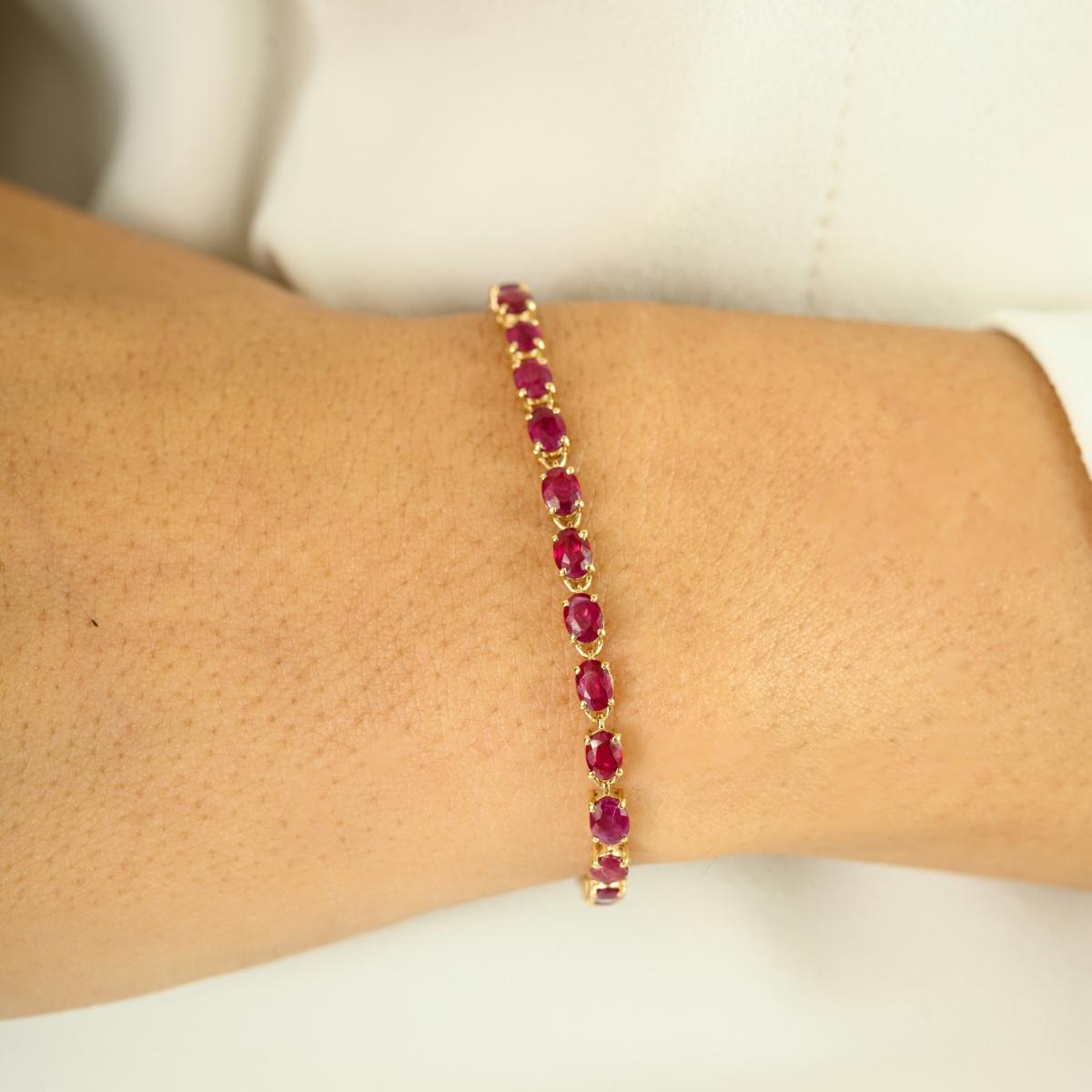 Confectionné en luxueux or jaune 14 carats, cet élégant bracelet de tennis est orné de 5,93 carats de rubis ovales éclatants qui scintillent à chaque mouvement. Chaque pierre est sertie de manière experte afin de créer un flux continu d'une riche