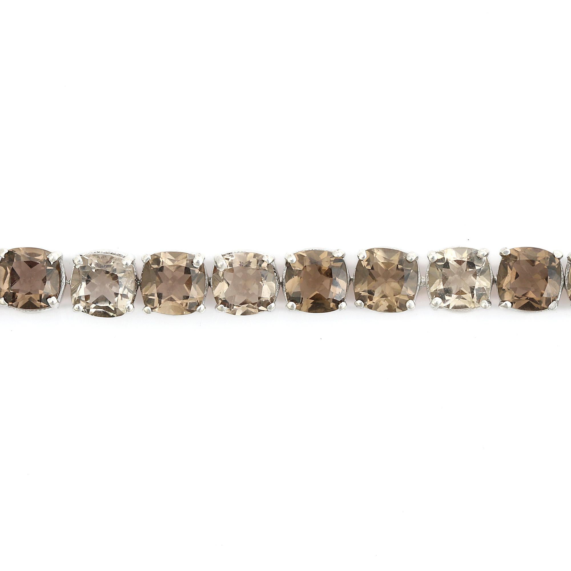 Questo braccialetto d'argento Tennis con Topazio Fumé incastonato è caratterizzato da una fila continua di gemme di quarzo fumé tagliate a cuscino e incastonate in un luminoso argento 925. Ogni pietra è incastonata in modo sicuro per massimizzare la