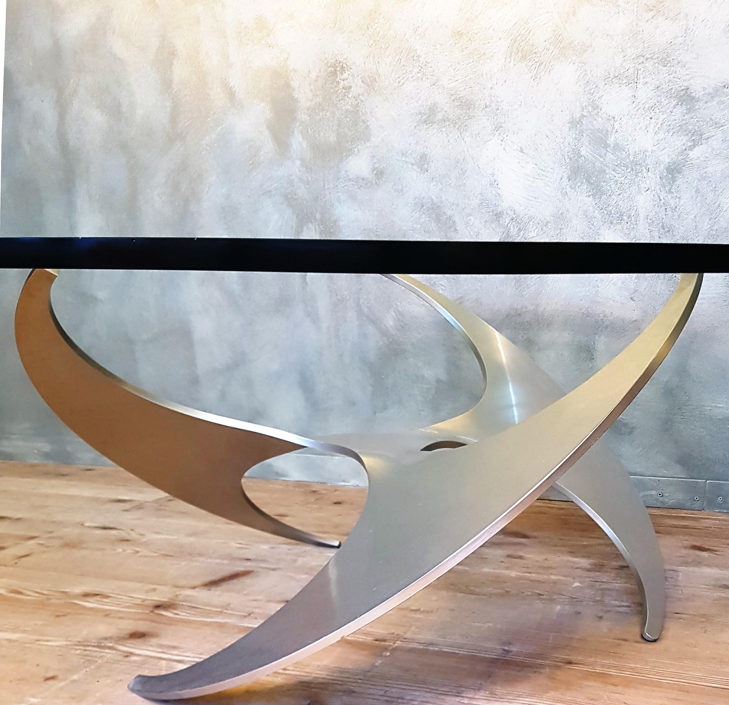 The sculptural foot is made of three rings of brushed aluminum. The 19mm thick glass top rests on glass protectors on this frame.