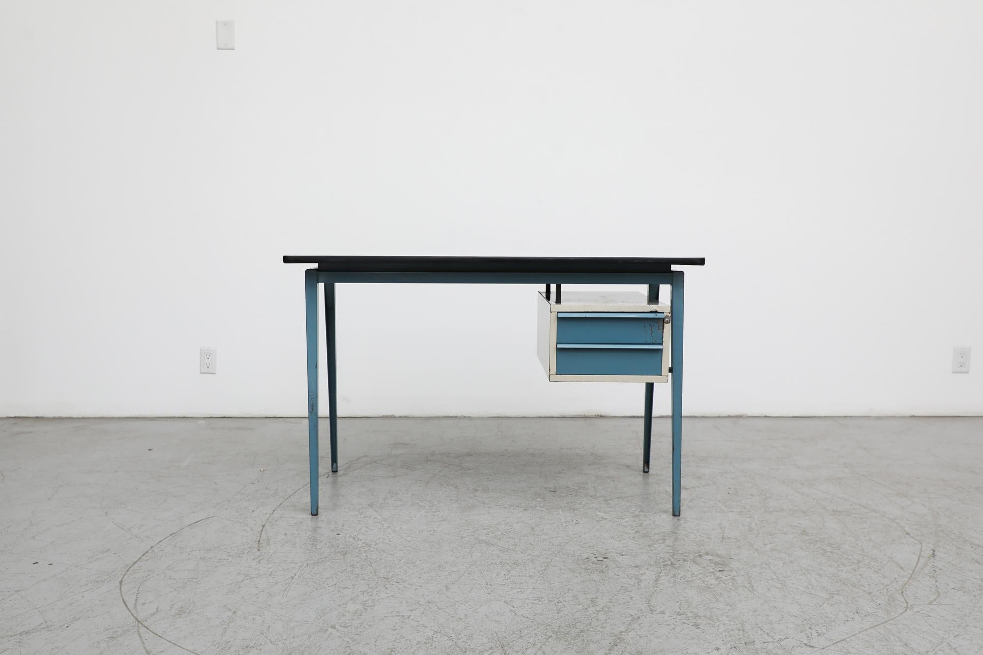 Prouve Inspired industrial writing desk by Marko. Formica top with blue enameled metal compass legs and one side cabinet with two blue drawers. Great for a loft space or work studio. The lock no longer functions. In very original condition with some