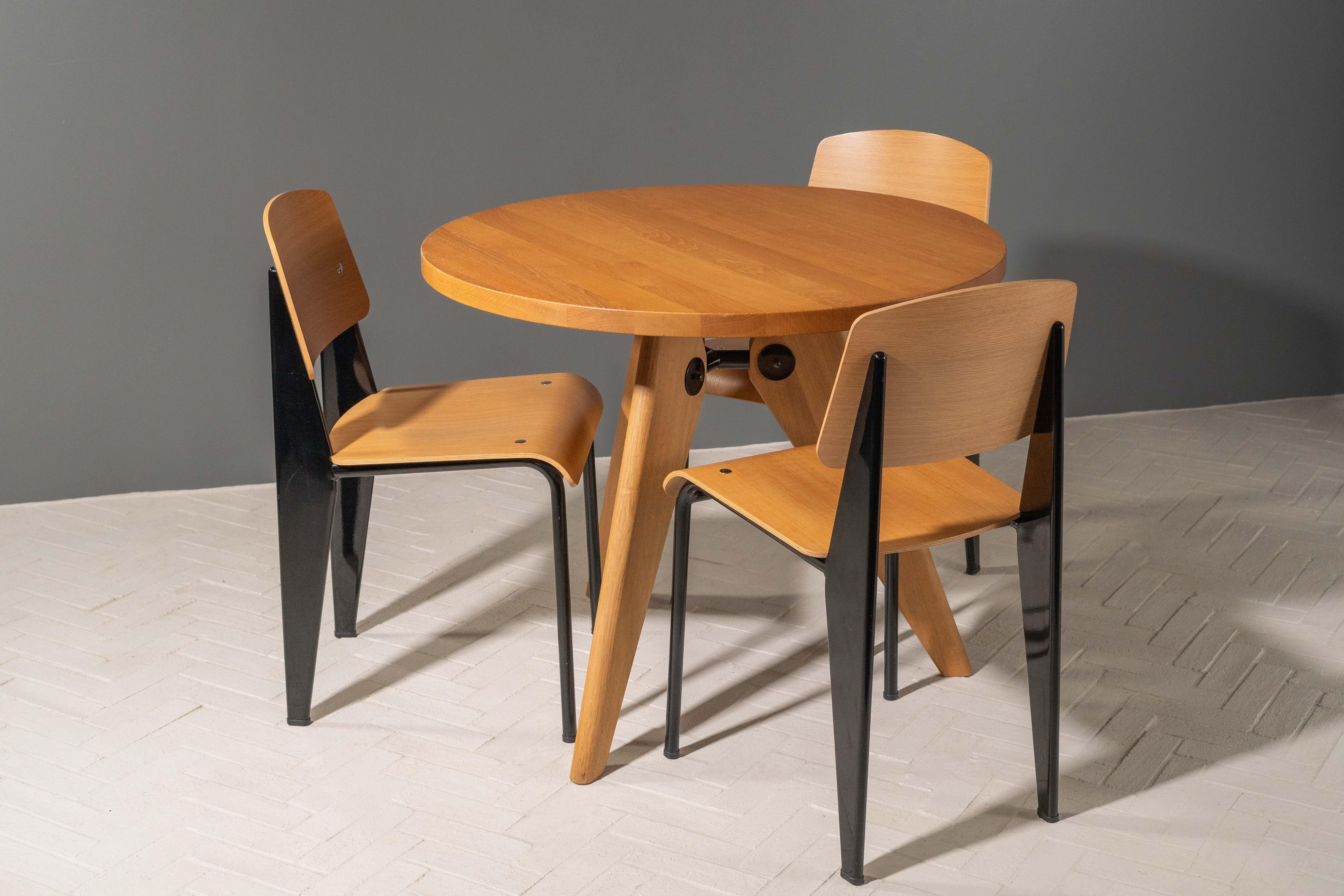 Germany, ca. 2016. A contemporary edition of Jean Prouvé's Guéridon Table with a set of three of his Standard Chairs by Vitra. Originally designed for the University of Paris in 1949, the table features solid oak construction with diagonal legs