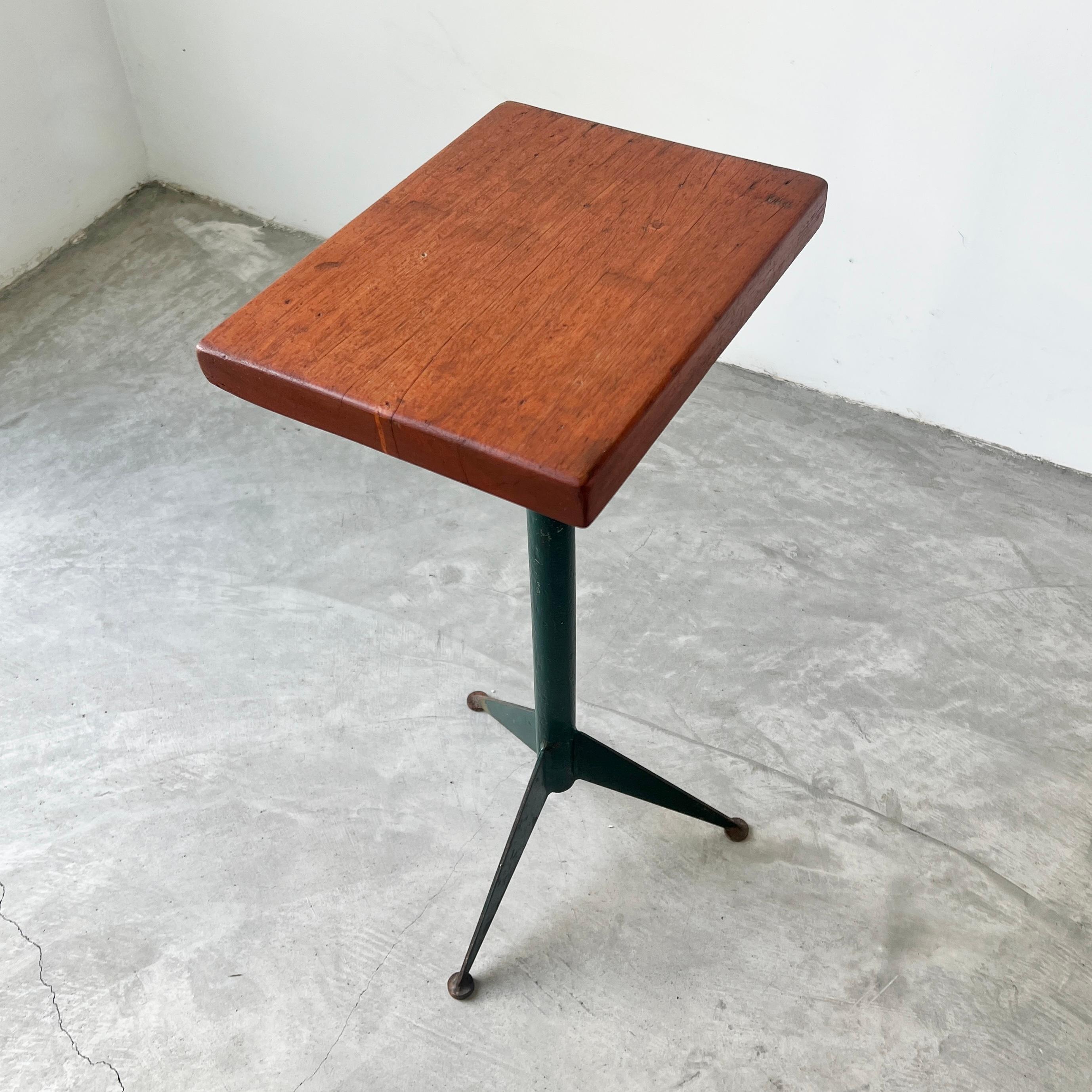 Un bijou minimaliste doté d'une grande personnalité. Cette table d'appoint du milieu du siècle présente un plateau en noyer chaleureux perché sur une base en métal vert de style Prouve avec des pieds tripodes. C'est un mélange parfait de raffinement