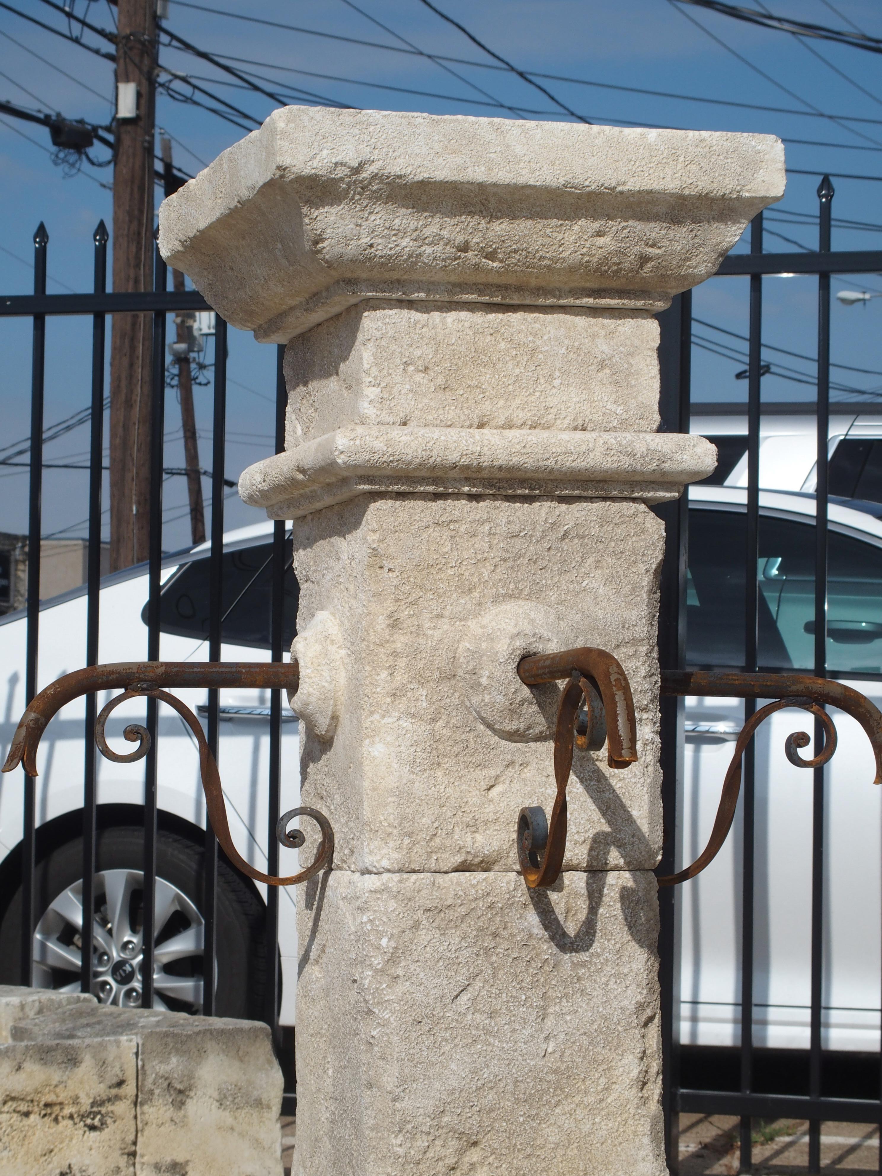 This hand carved limestone, center fountain from France is octagonal and has well shaped basin stones instead of flat sides. It has four iron S-scroll spouts that adorn the center post, and the basin has two iron bars for holding flower pots or
