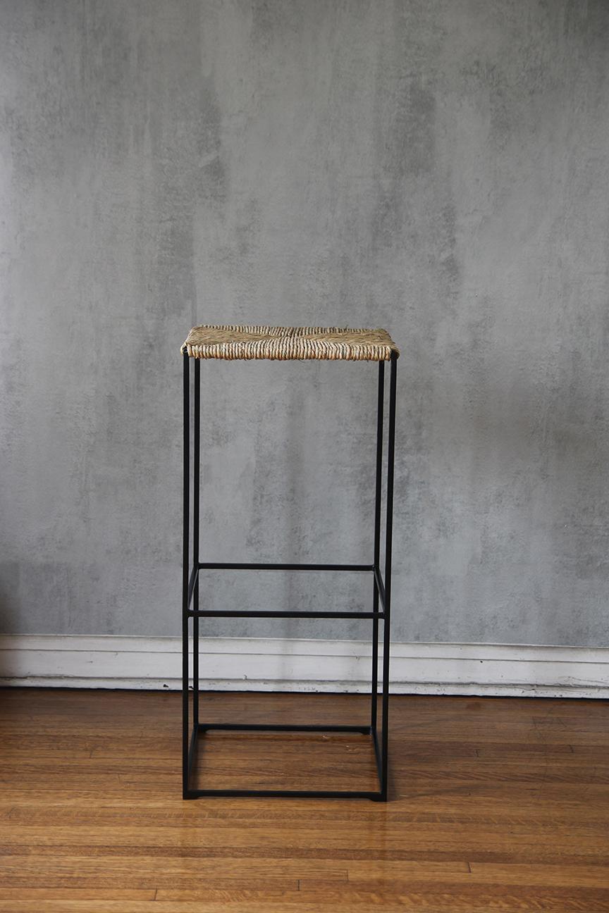 'Provence' counter height stools by Understated Design. Chic combination of slender but sturdy powder coated steel frames with handwoven rush seat. Elegant detail on the bottom part of the stool. 
Simple , Elegant, chic and Understated. 
Additional