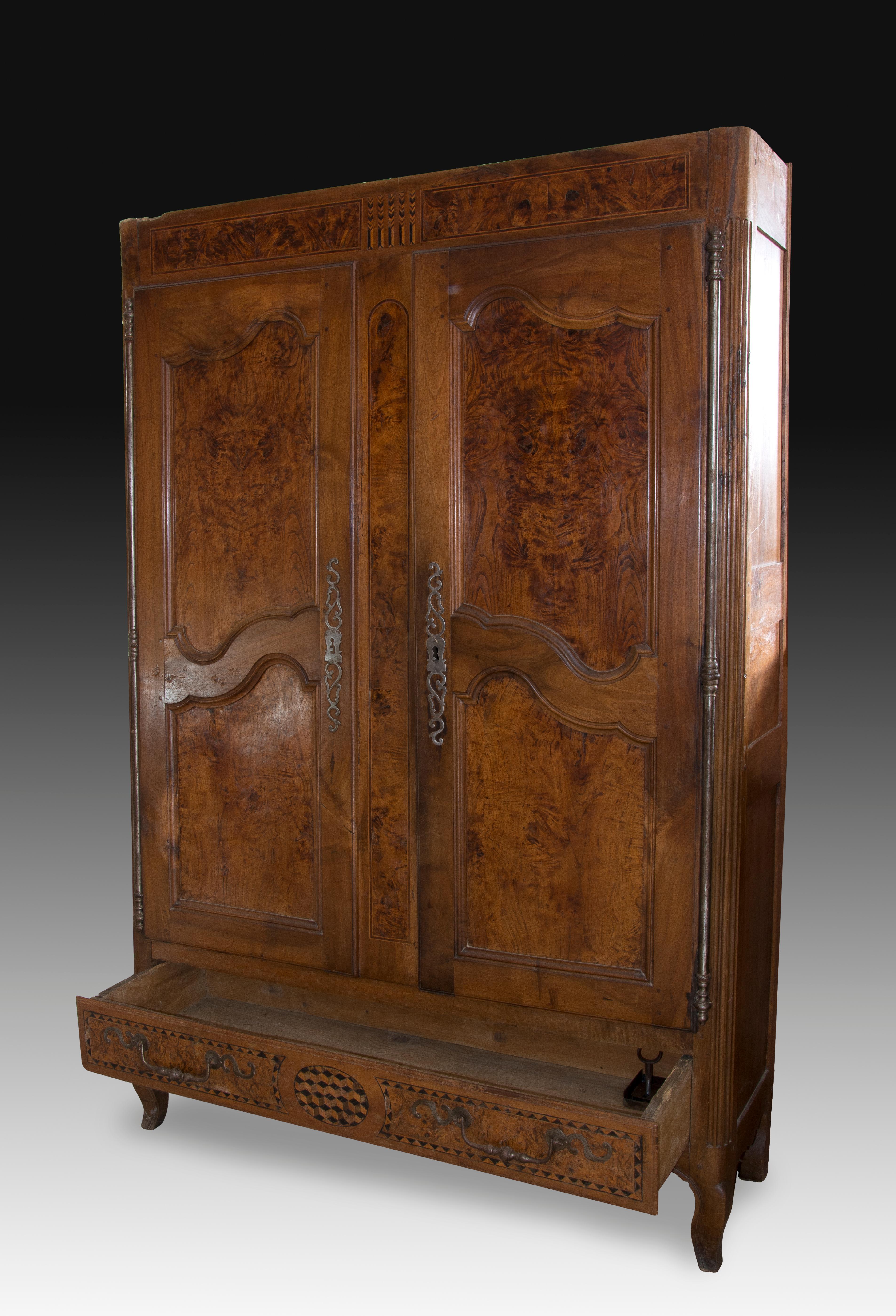 Armario de estilo provenzal. Madera de nogal y raíz, herrajes de hierro forjado. Siglo XVIII. 
 Falta el embellecedor superior. Armario de dos puertas con un cajón en la parte inferior elevado sobre dos patas en forma de cabriolé y decorado en el
