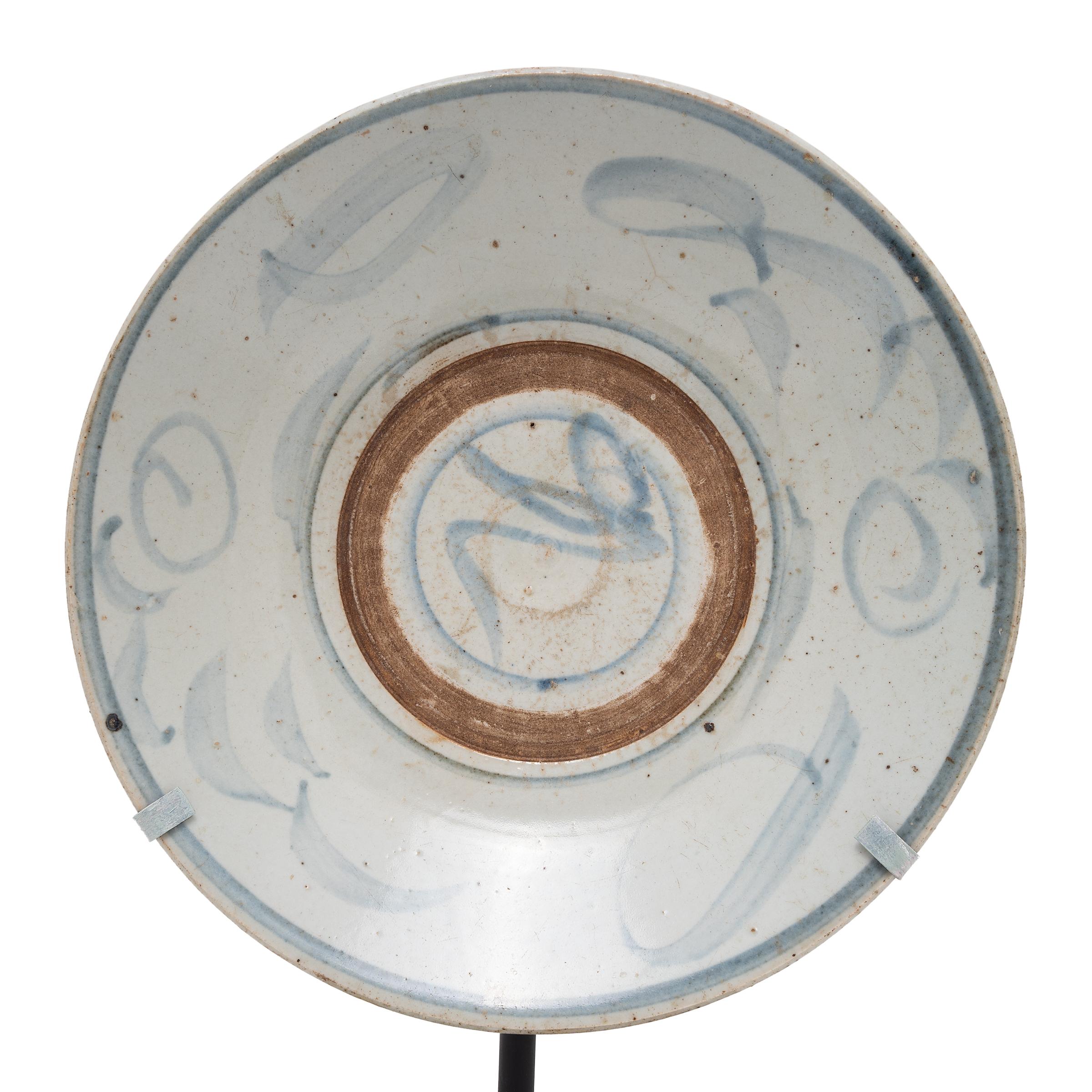 Calligraphic sweeps of blue bring this 19th-century footed plate to life, brushed atop a blue-grey glaze that cloaks its simple ceramic form. Once used as an everyday serving dish, this rustic plate has been reimagined as a tabletop sculpture,