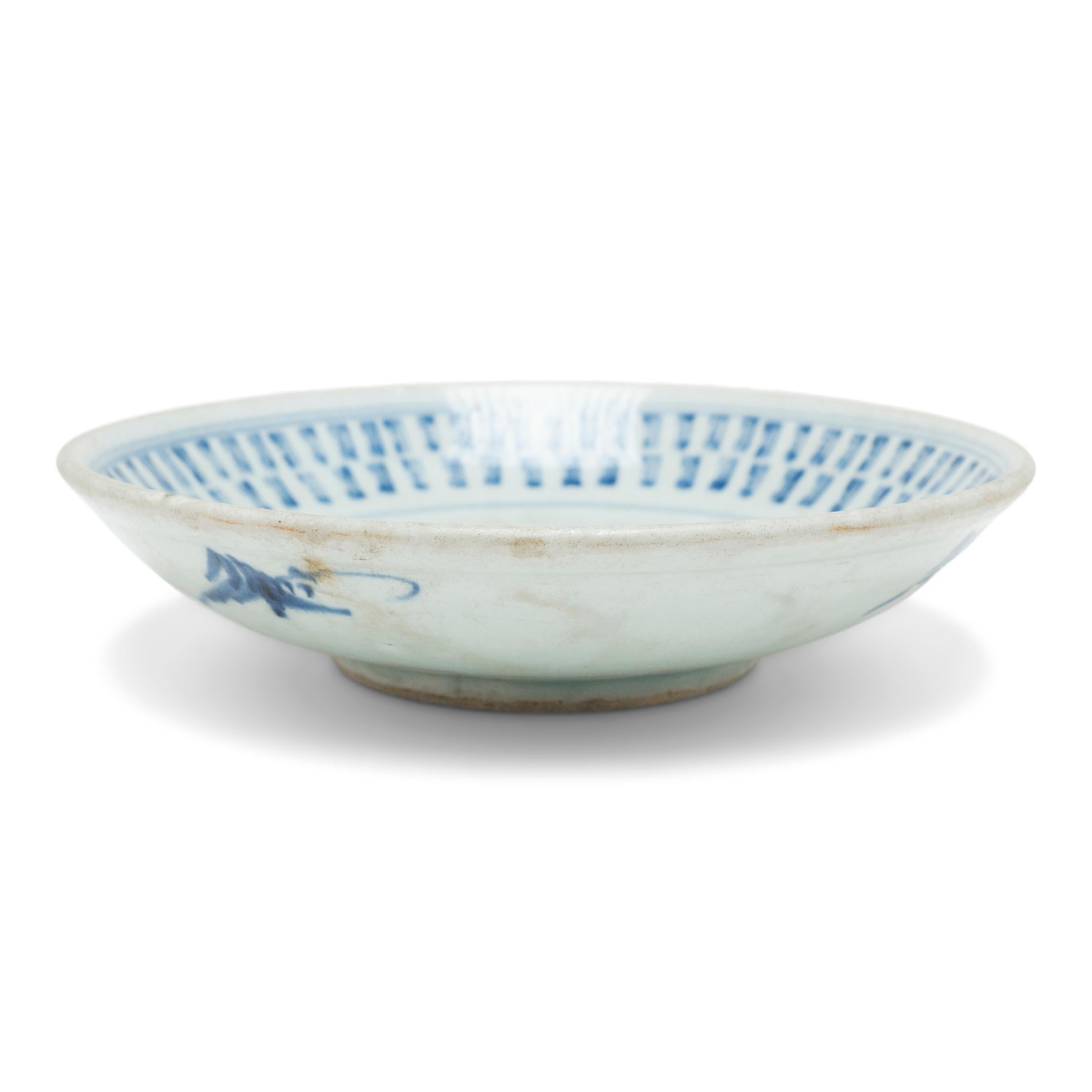 Cette assiette à pied du milieu du XIXe siècle est décorée dans le style bleu et blanc d'un motif géométrique et curviligne estampé. Au centre de l'assiette se trouve un médaillon en forme d'étoile rempli de méandres floraux et entouré d'une bordure
