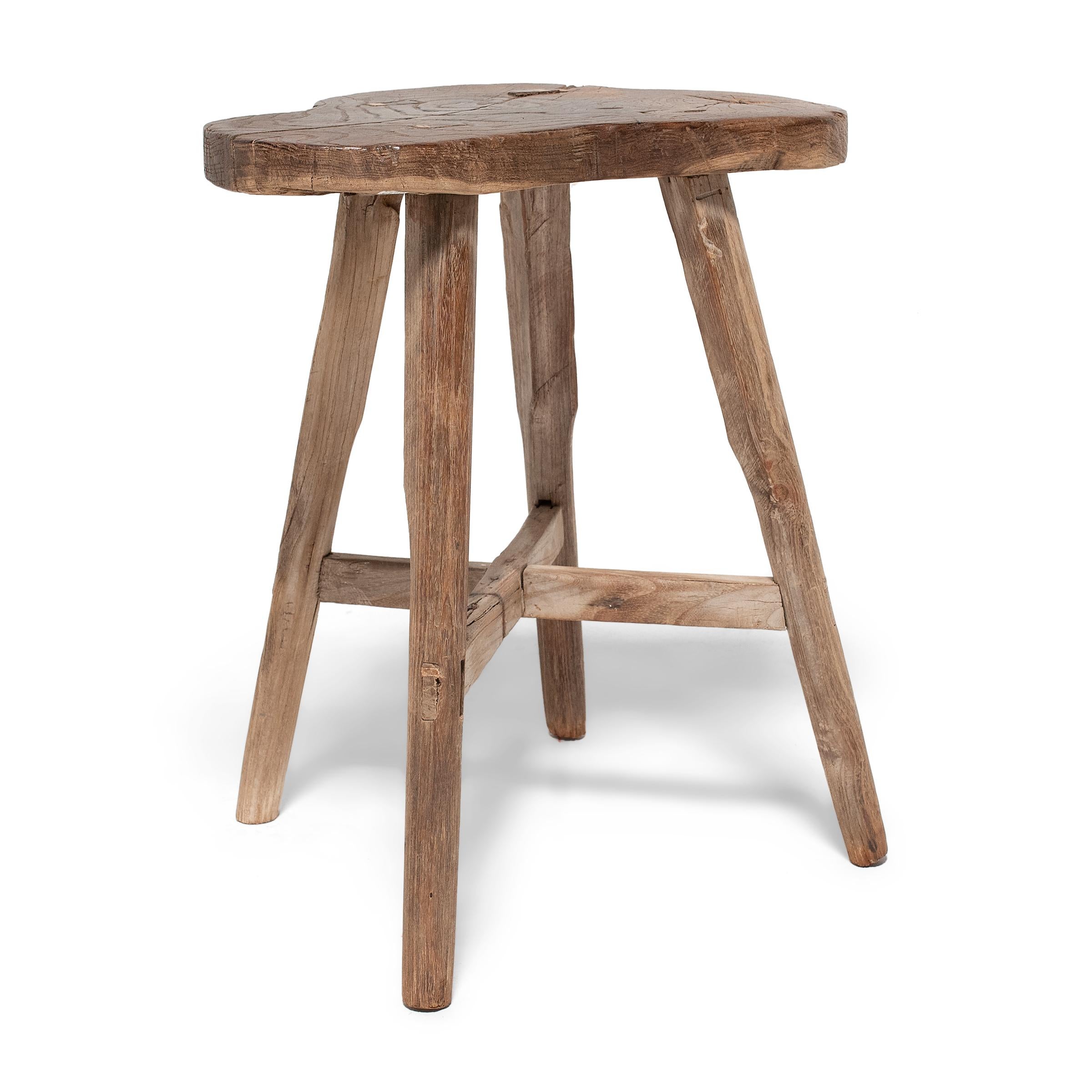 Crafted of Chinese northern elm (yumu) using mortise-and-tenon joinery, this everyday stool from Shandong province charms with timeless rustic appeal. Four thin legs support linked by crossed stretchers support a trefoil seat shaped to resemble a