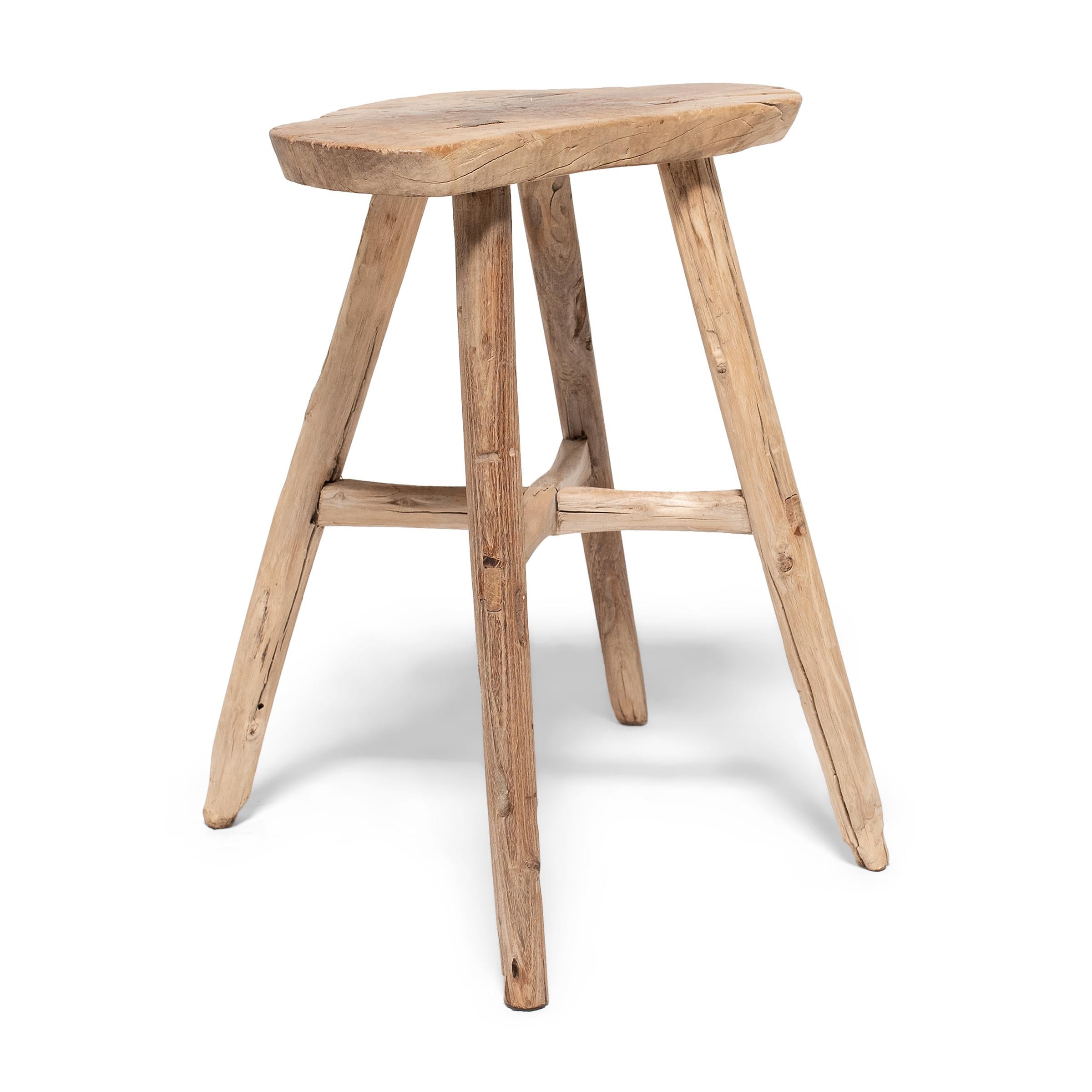 Crafted of Chinese northern elm (yumu) using mortise-and-tenon joinery, this everyday stool from Shandong province charms with timeless rustic appeal. Four thin legs support linked by crossed stretchers support a trefoil seat shaped to resemble a
