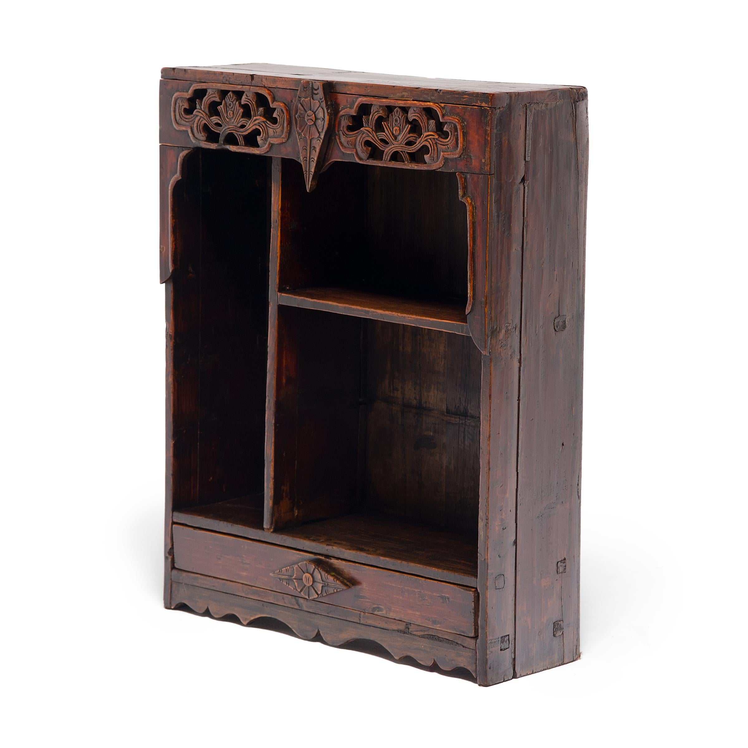 This provincial collector's shelf features three open compartments enclosed by a decorative frame carved with abstract floral motifs. Dated to the late 19th century, the shelf once stood in an office or home studio, displaying a curated collection