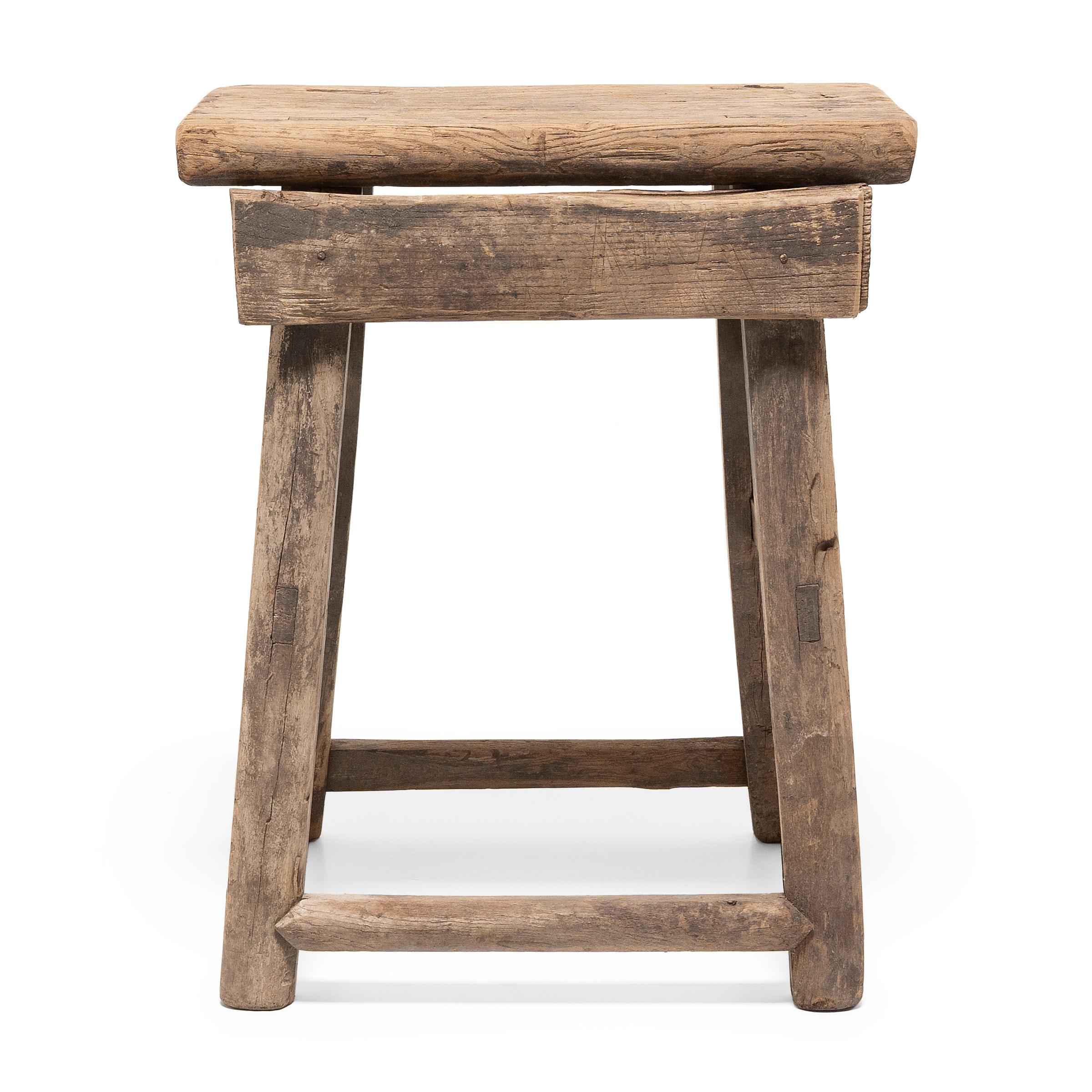 Dated to the turn of the century, this provincial stool would have been used throughout a courtyard home as versatile everyday seating. Hand-crafted of pine, the tapered stool has a rectangular seat supported by four splayed legs, each linked with