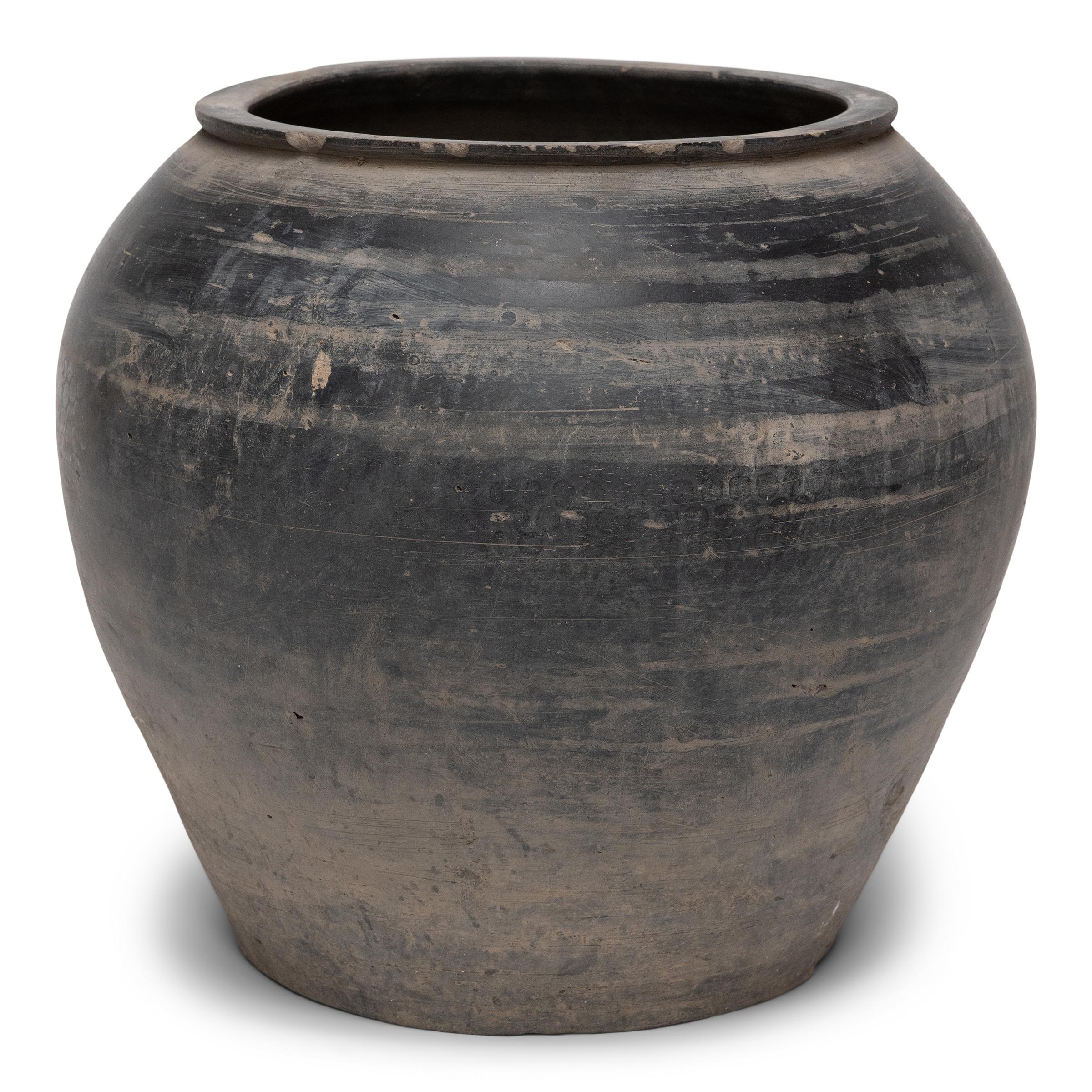 This ceramic vessel from Shanxi province has a smoky grey-taupe exterior with balanced proportions and a matte, unglazed finish. Charged with the humble task of storing dry goods, the earthenware jar has a tapered form with rounded shoulders and a
