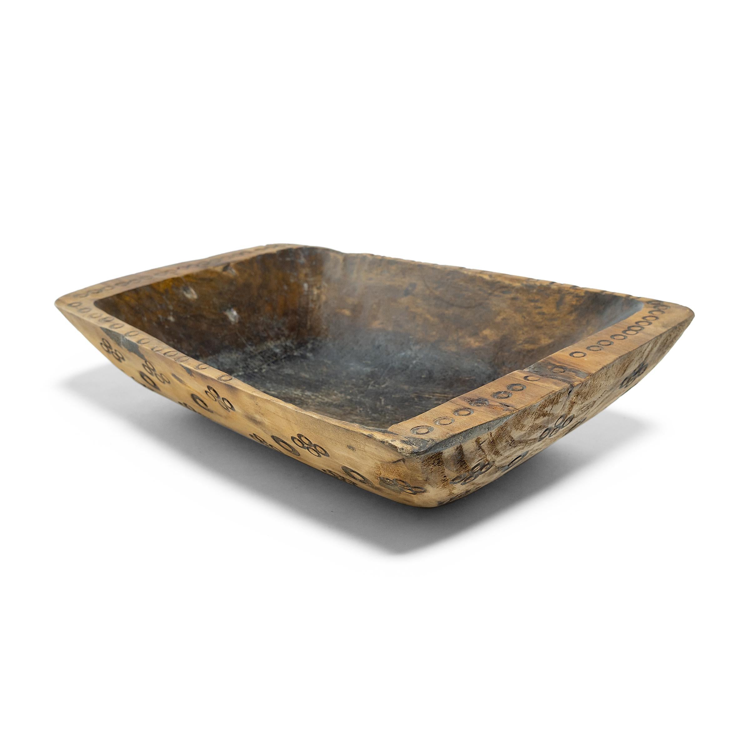 This wooden farm tray from northern China charms with its rustic finish and asymmetrical form. Hand-carved from a single block of wood, the large tray is truly one-of-a-kind, shaped to follow the natural contours of the wood. The exterior has been
