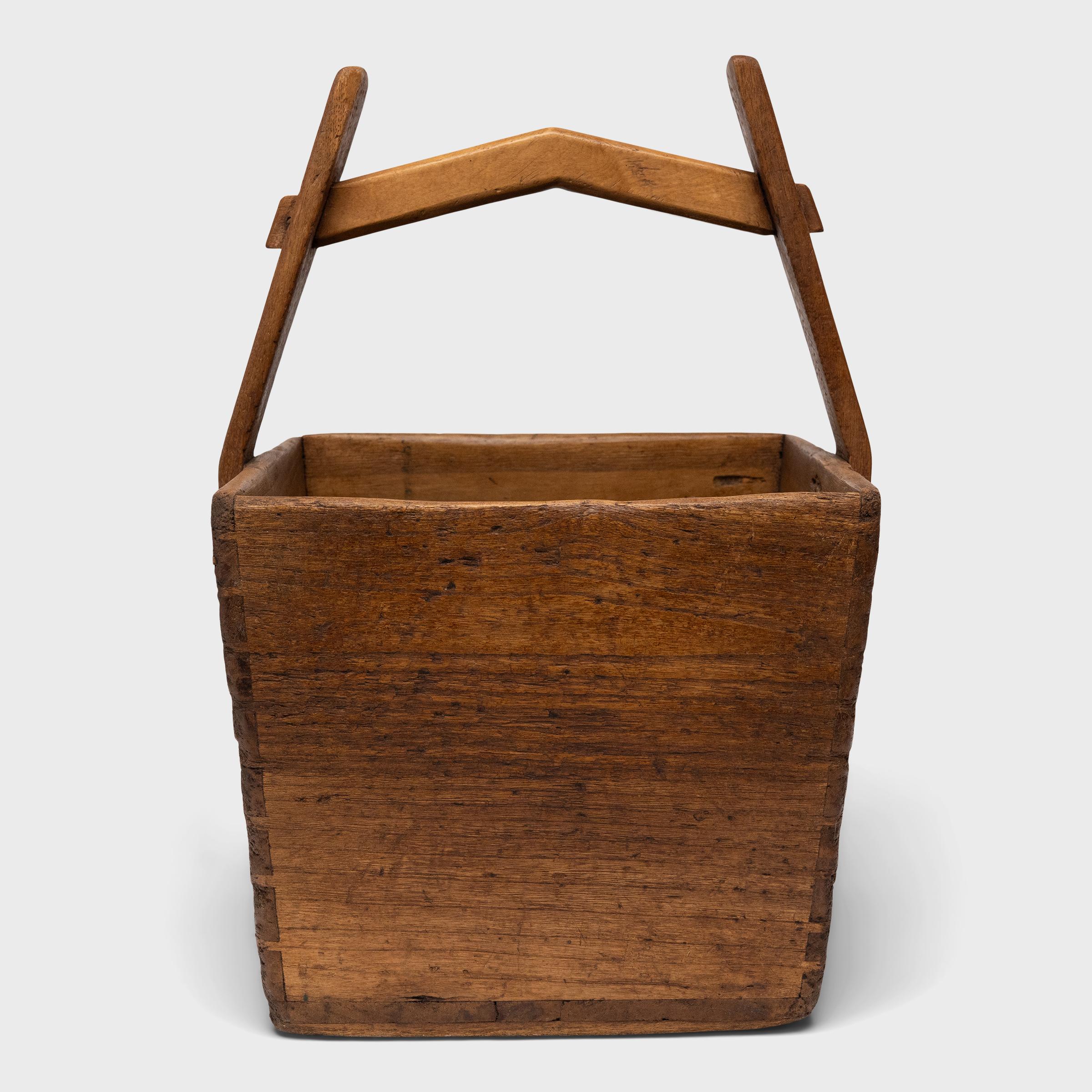This hand-crafted wooden bucket was once used by farmers in Shandong, China to transport their harvest of grains and other crops over long distances. Counterbalanced by a second container, the pail would have been lifted by a pole threaded through
