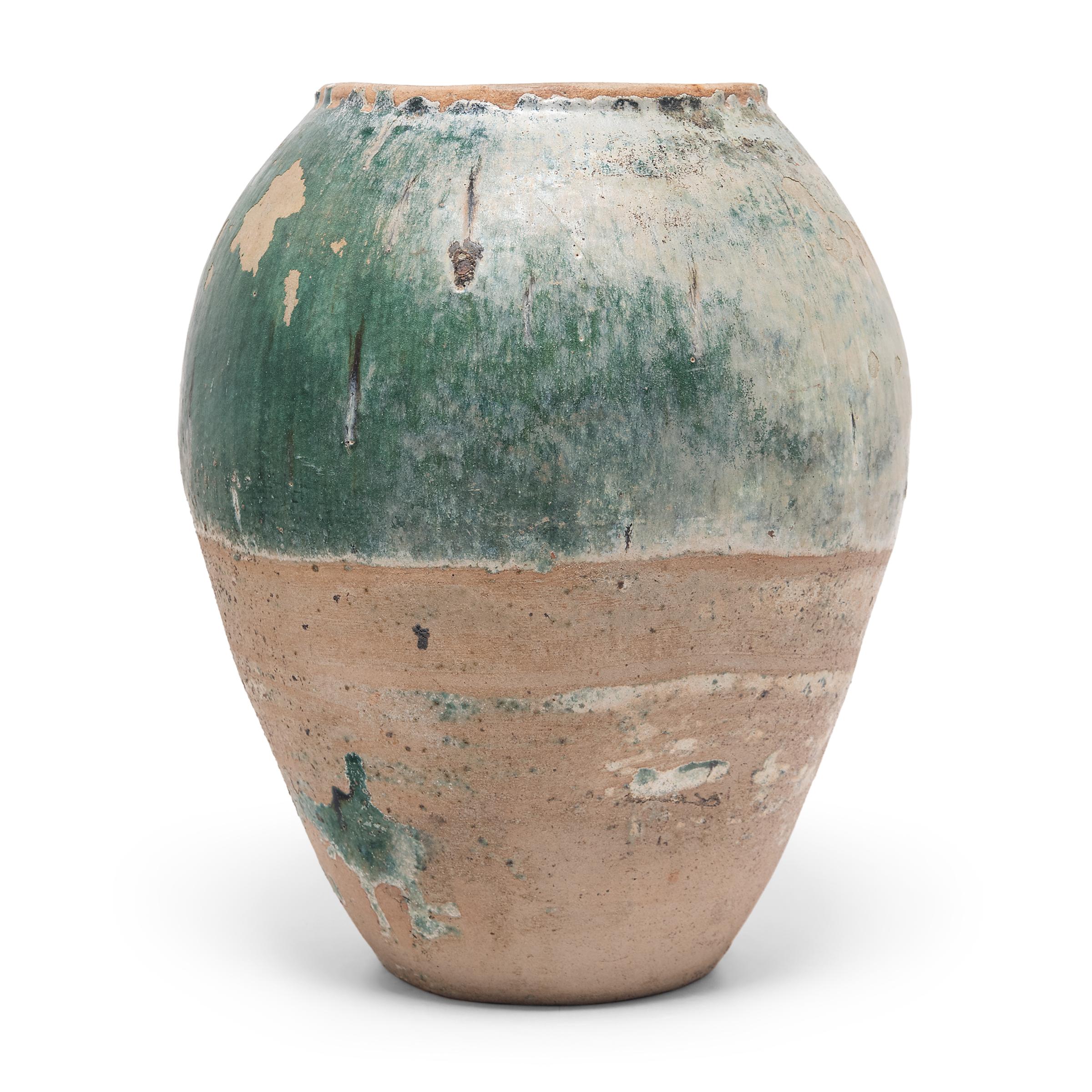 Charged with the humble task of storing dry goods, these large earthenware jars are distinguished by their tapered forms and beautifully imperfect glazed exteriors. The upper half of each vessel is coated in crackled overglaze that transitions from