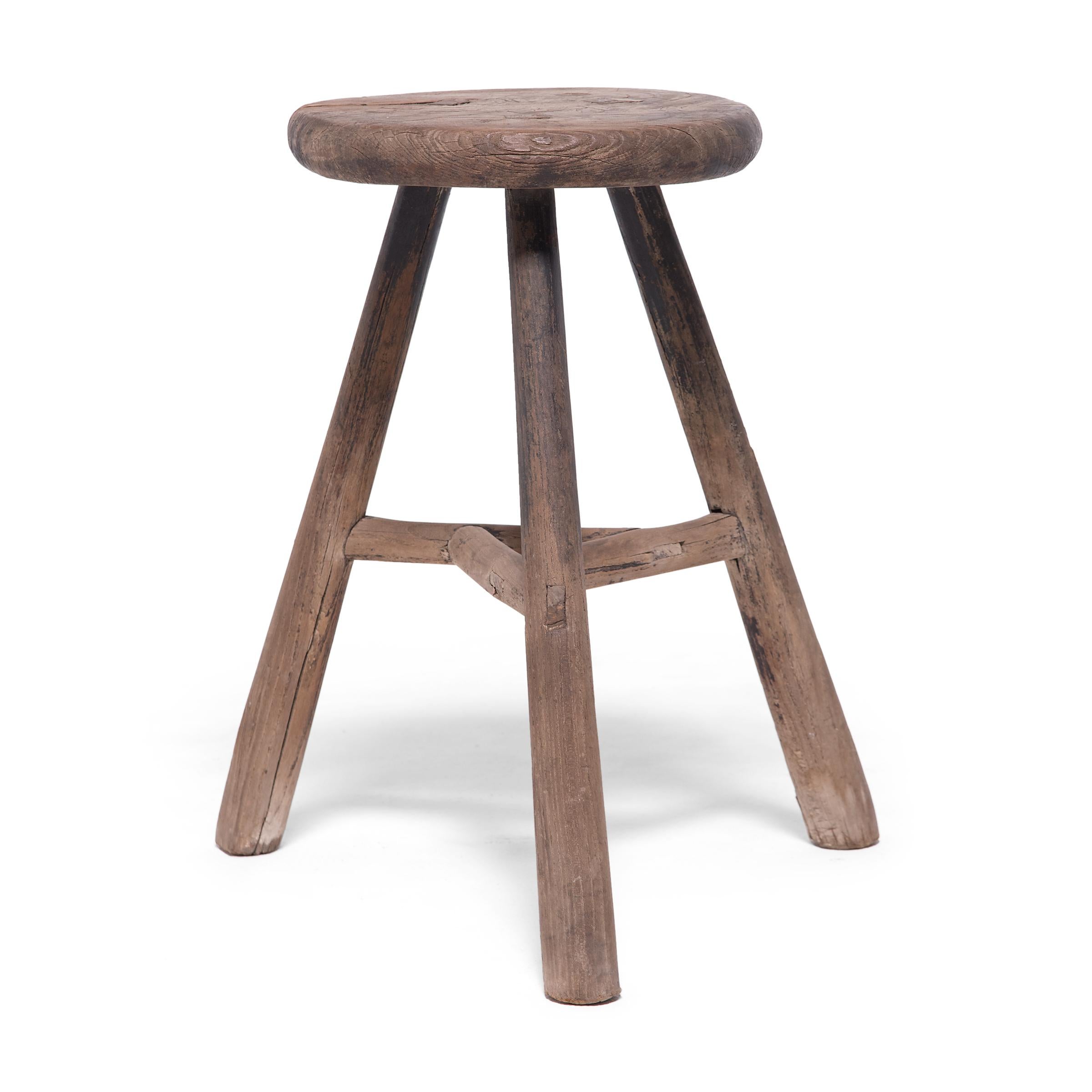 Deceptively simple, this rustic stool from the early 20th century shows off the ingenious joinery methods traditionally used by Chinese carpenters. The stool's three splayed legs are supported by stretcher bars that interlock at the center to form a