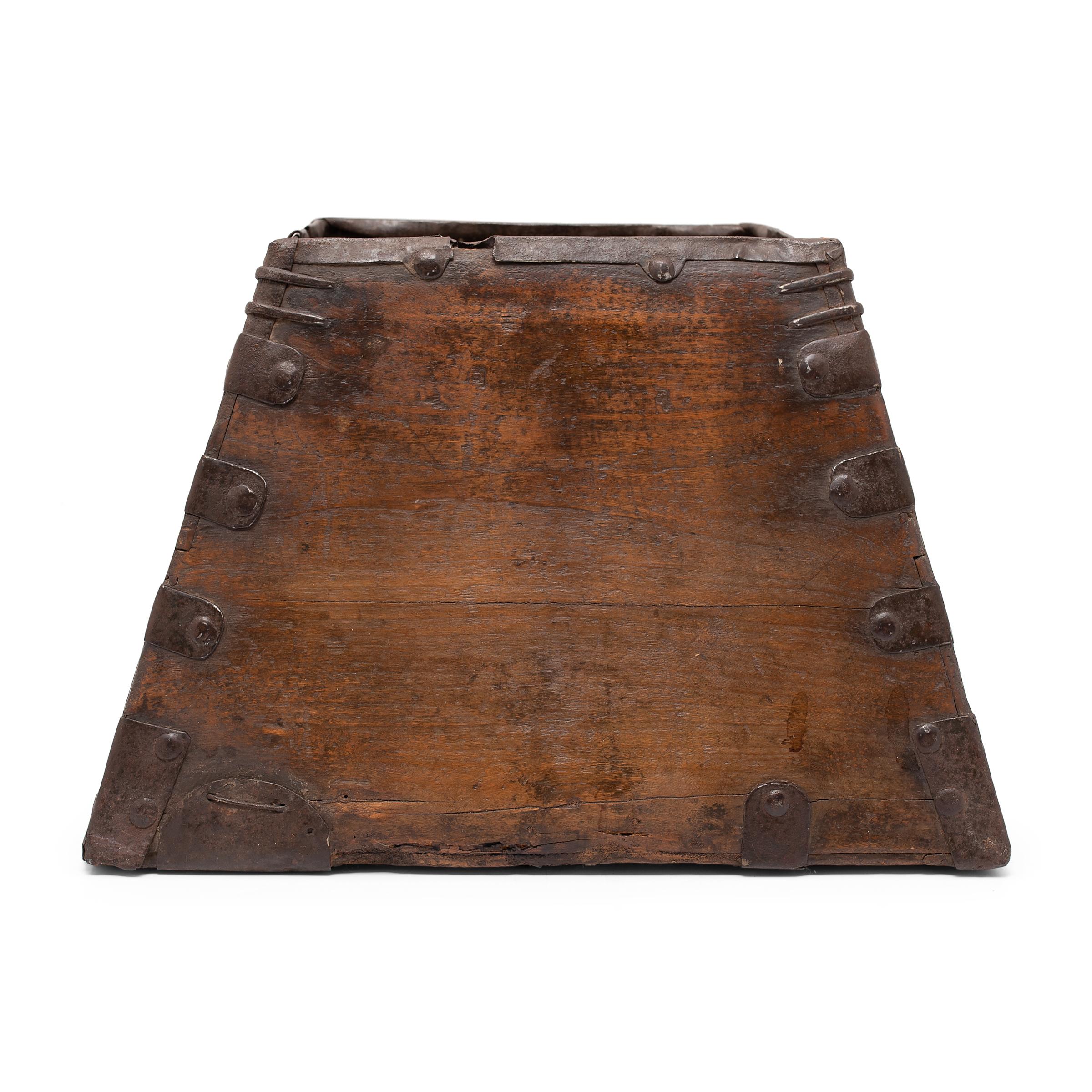 This rustic container was made over a hundred years ago to measure and hold a dou of rice, an ancient Chinese measurement. The rice measure has a square form with tapered sides and edges trimmed with iron fittings to protect against damage. This