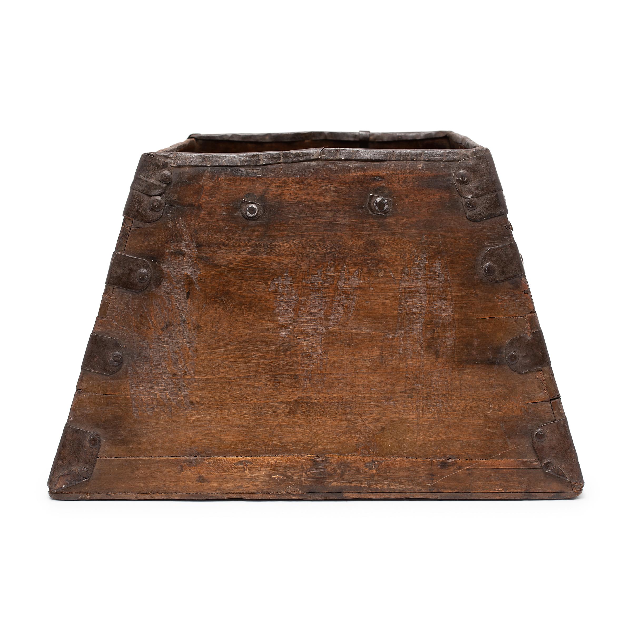 This rustic container was made over a hundred years ago to measure and hold a dou of rice, an ancient Chinese measurement. The rice measure has a square form with tapered sides and edges trimmed with iron fittings to protect against damage. This