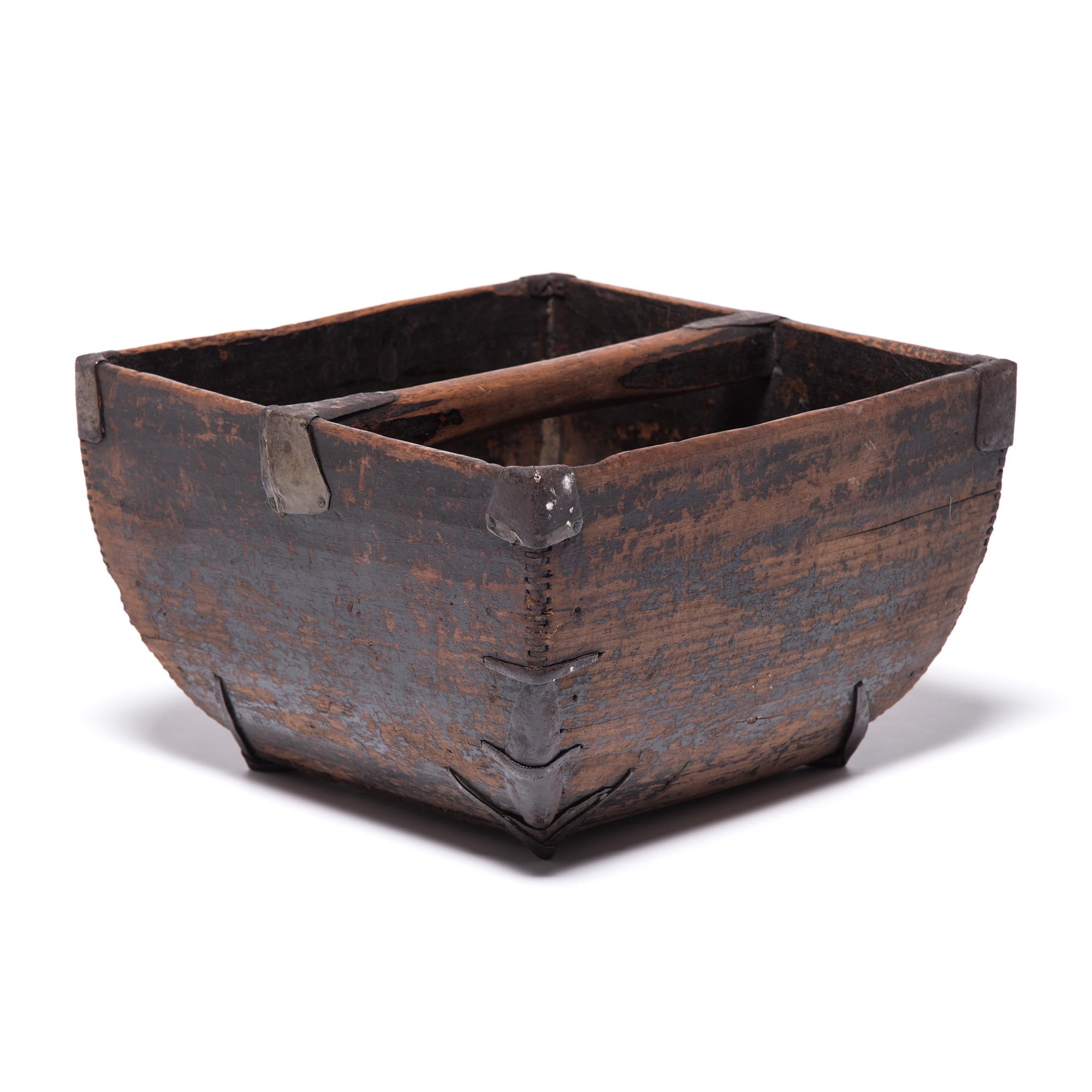 This rustic container was made over a hundred years ago to measure and hold a dou of rice, an ancient Chinese measurement. It is handcrafted with thin finger joints, iron-finished edges, and a subtly arched handle. Antique iron repairs reinforce the